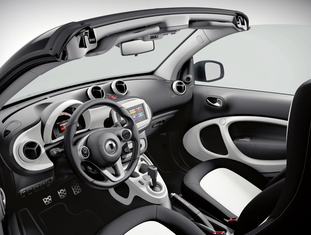 Innenraum eines modernen Autos mit offenem Verdeck, schwarzem und weißem Interieur, Multifunktionslenkrad und digitalem Display.