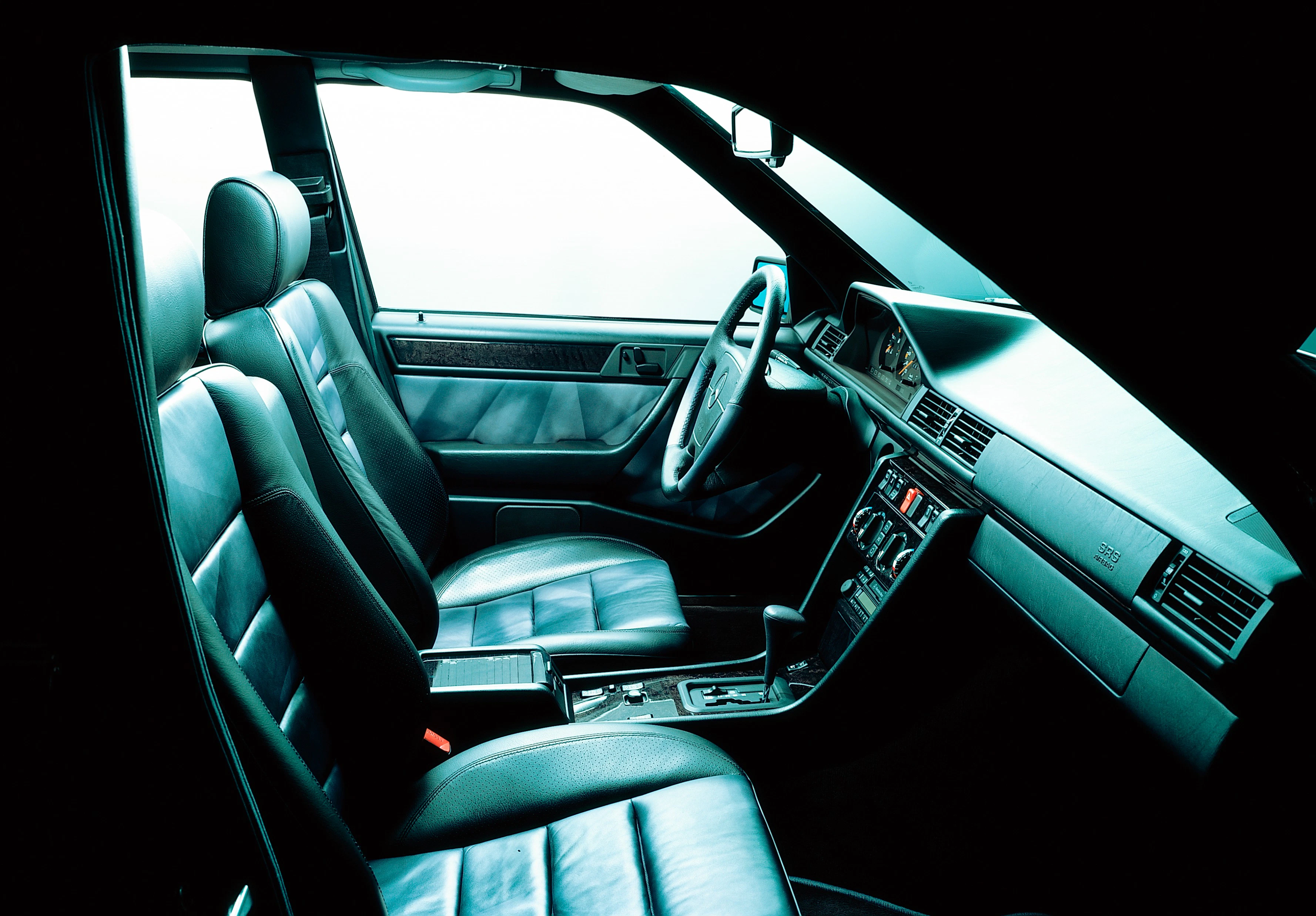 Innenraum eines klassischen Autos mit Ledersitzen, Lenkrad und Armaturenbrett. Beleuchtung erzeugt eine stilvolle Atmosphäre.