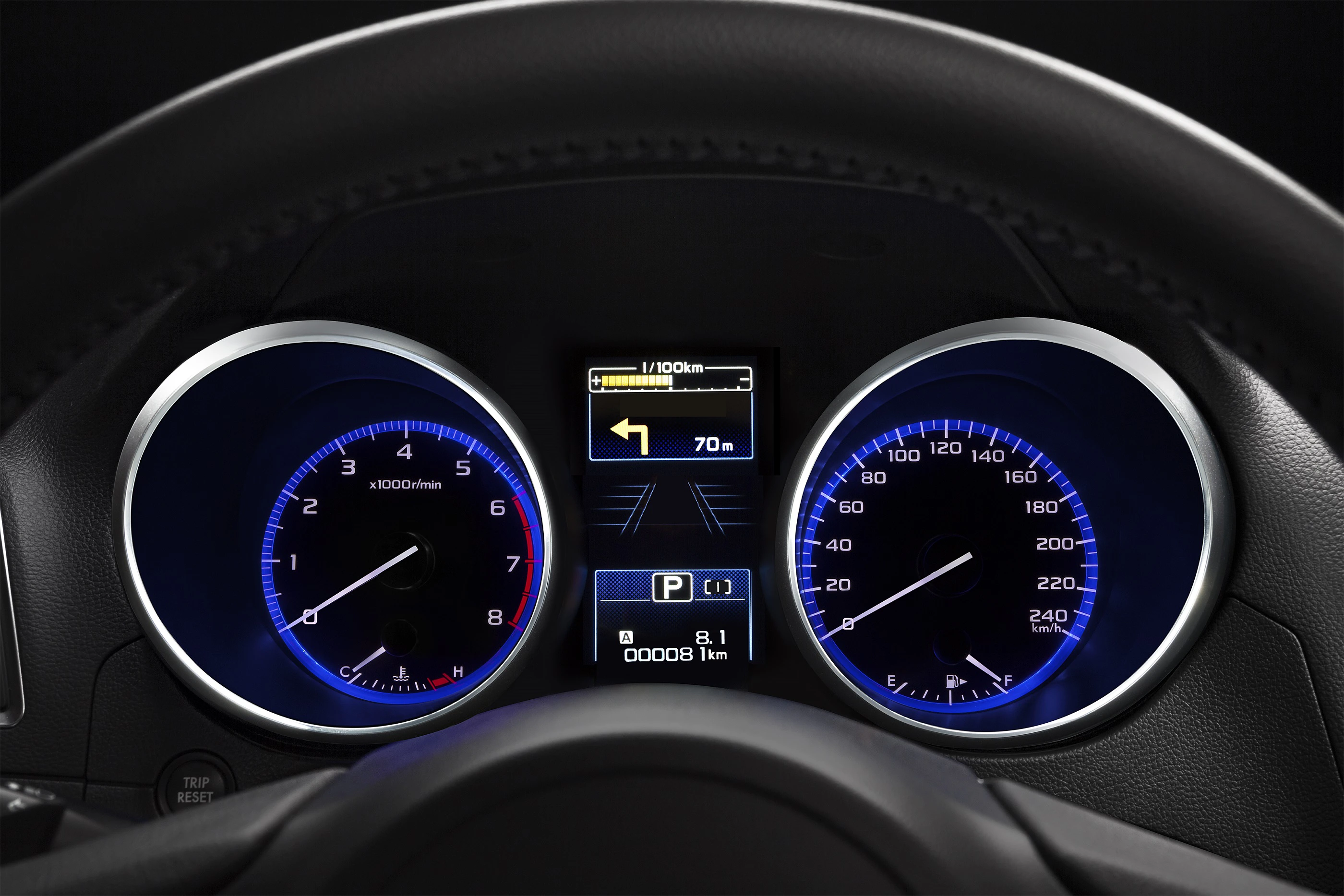 Nahaufnahme eines Autotachos mit blauer Beleuchtung, zeigt Geschwindigkeit, Drehzahl, Tankanzeige und digitale Anzeige mit Navigationspfeil.