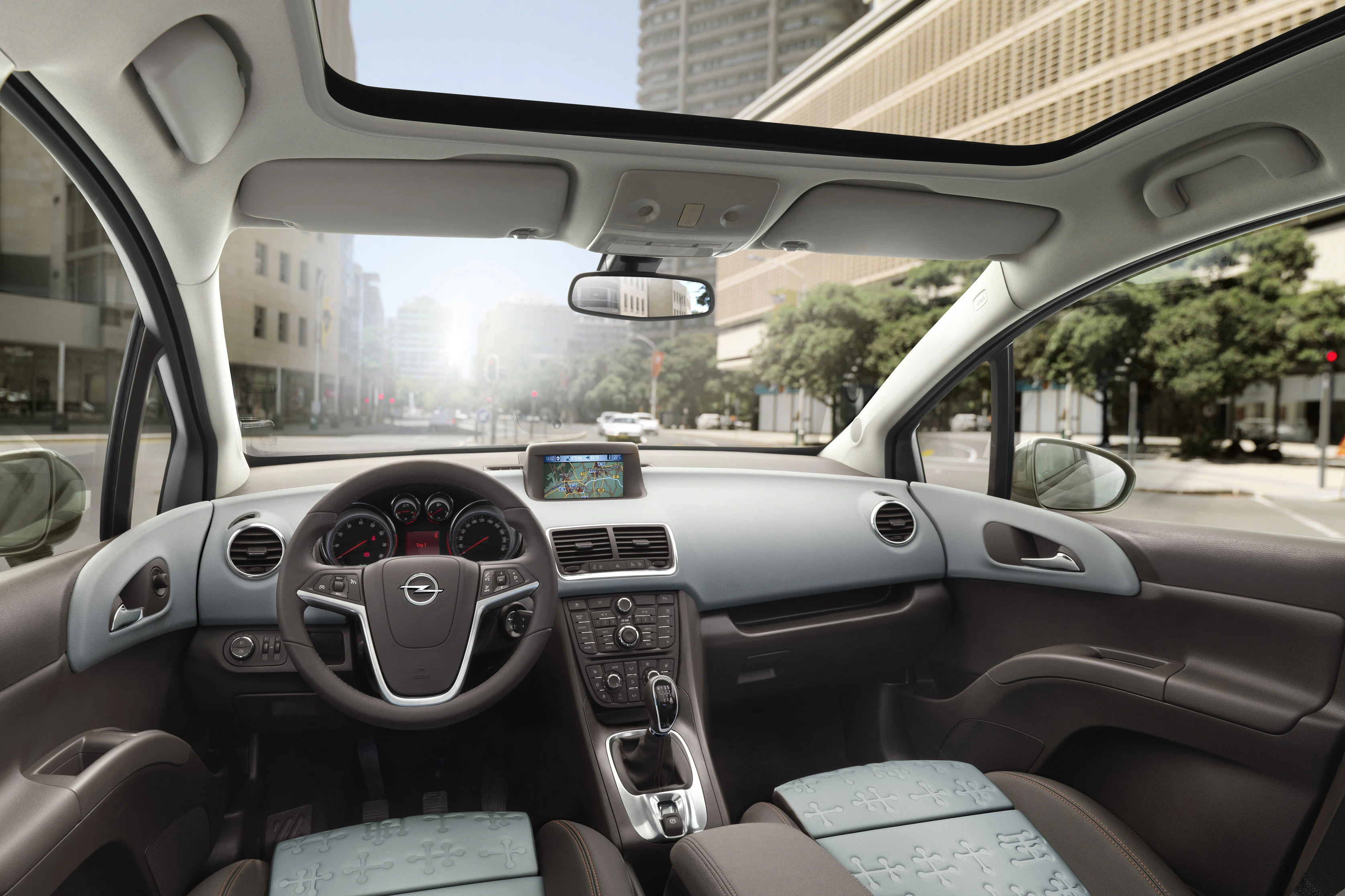 Innenraum eines modernen Autos mit Navigationssystem, Panoramadach und hellem Stadtblick durch die Windschutzscheibe.