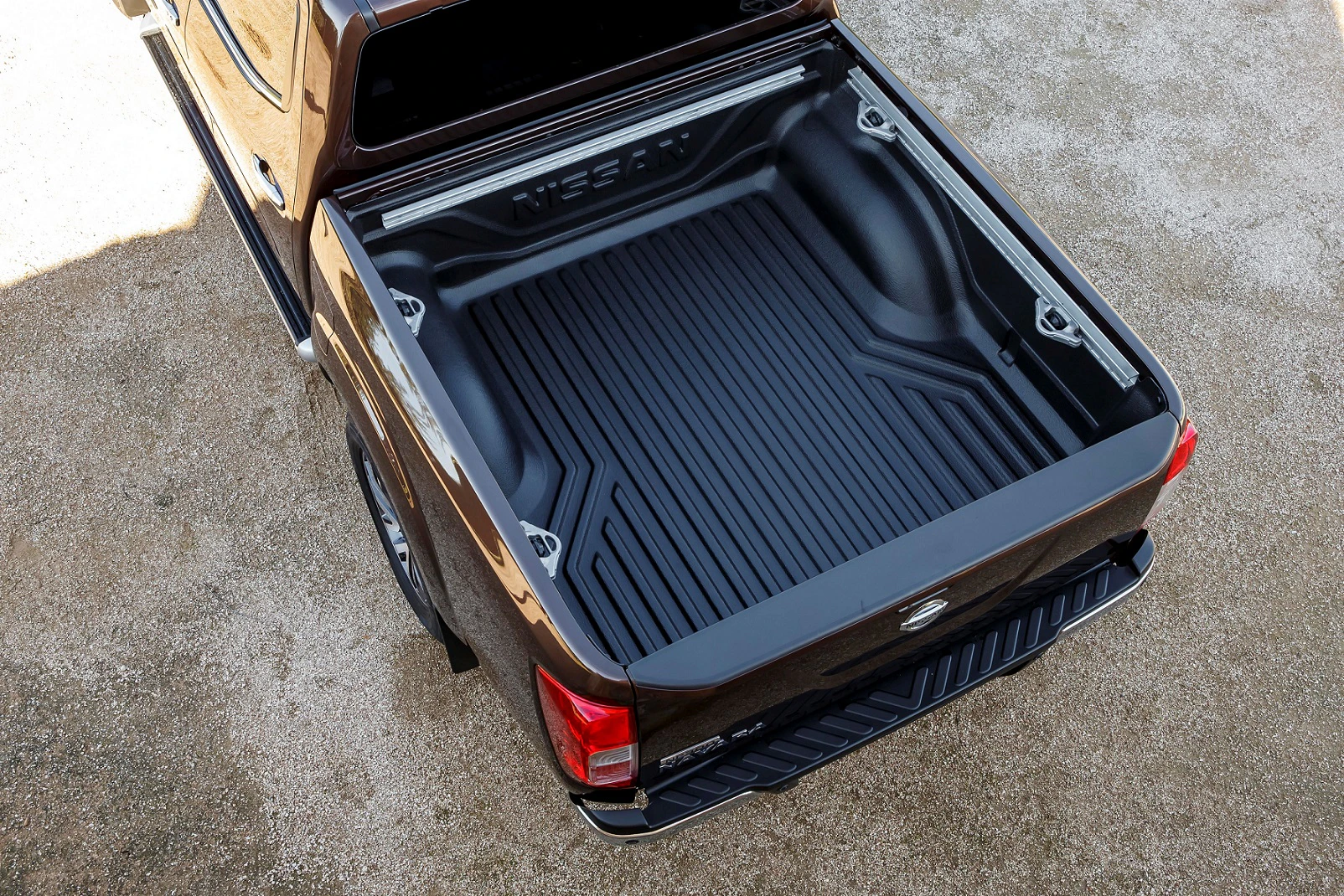 Obenansicht eines leeren, sauberen Pickup-Ladefläche, schwarz gefüttert, auf unbefestigtem Untergrund geparkt.