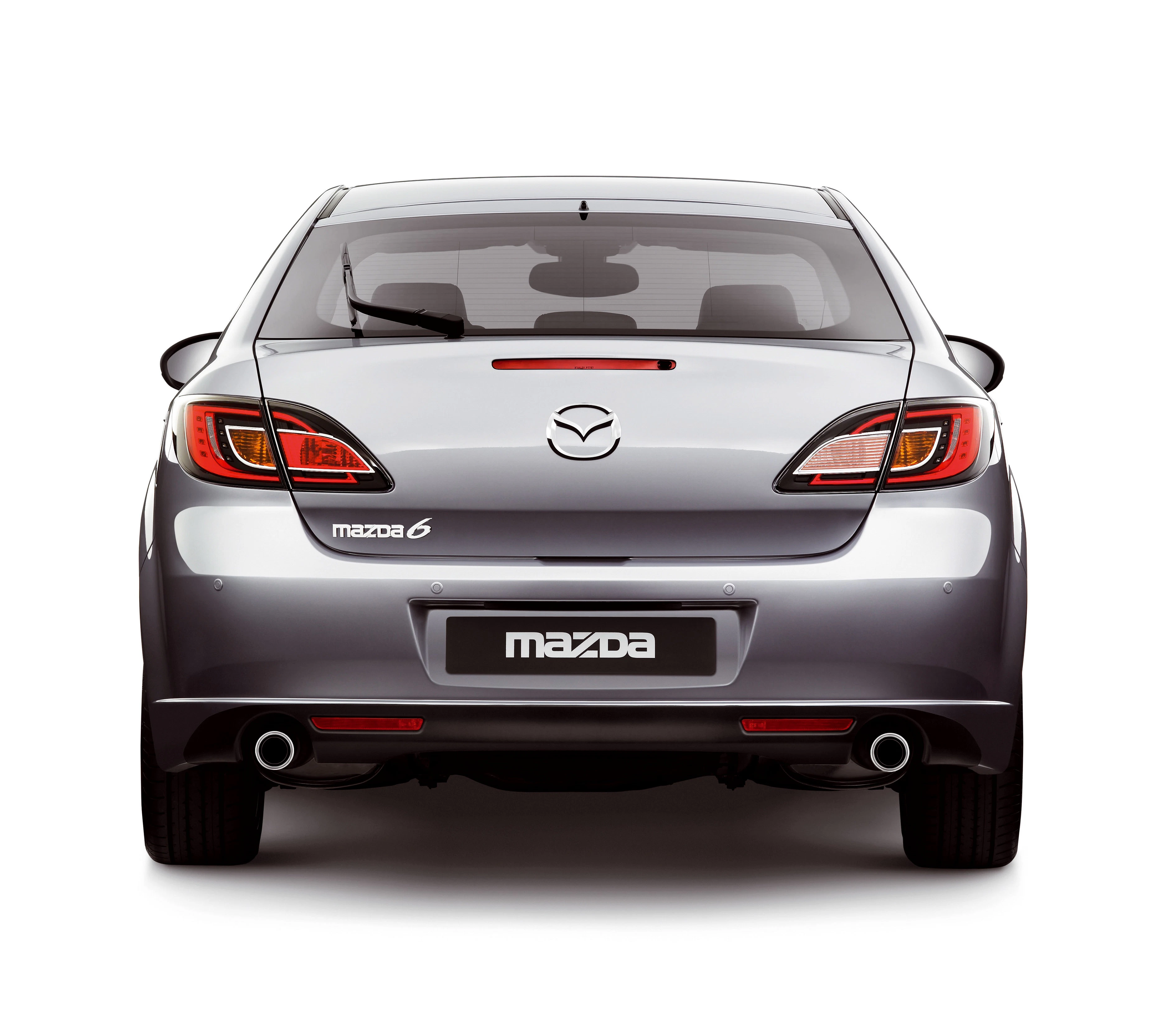 Rückansicht eines silbernen Mazda 6, hervorgehobene Rückleuchten und Auspuffrohre, auf weißem Hintergrund.