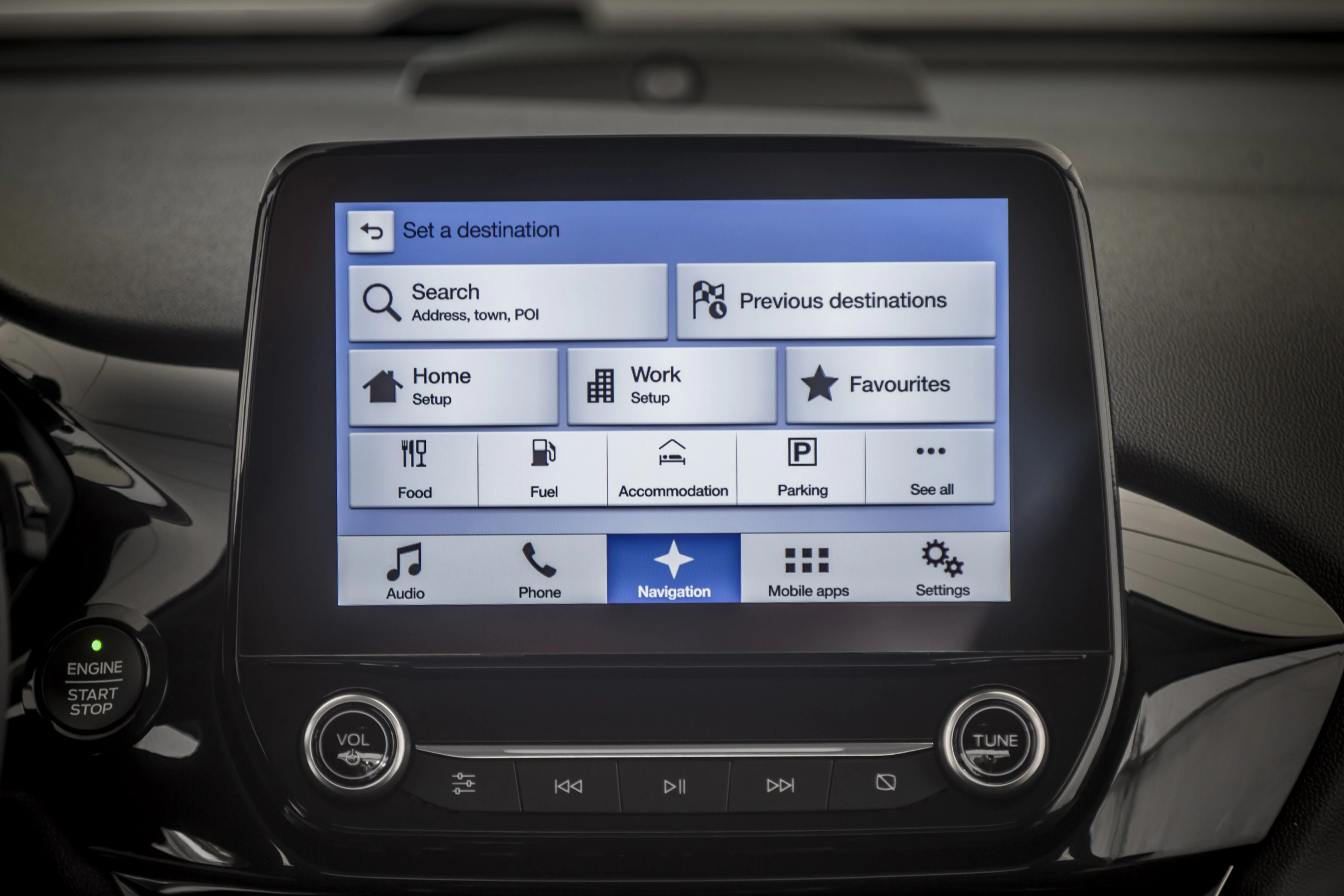 Multifunktions-Touchscreen in einem Auto mit Navigations-, Audio- und Einstellungsoptionen, einschließlich Zieleingabe und Favoriten.