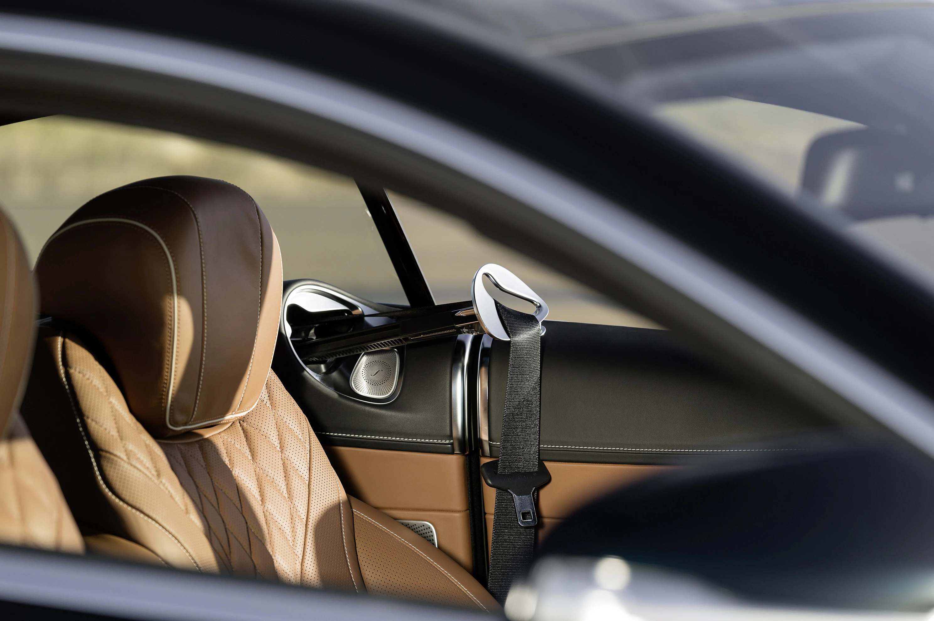 Nahaufnahme des Innenraums eines Luxusautos mit beigefarbenem Ledersitz und Akzenten in Chrom und Schwarz.