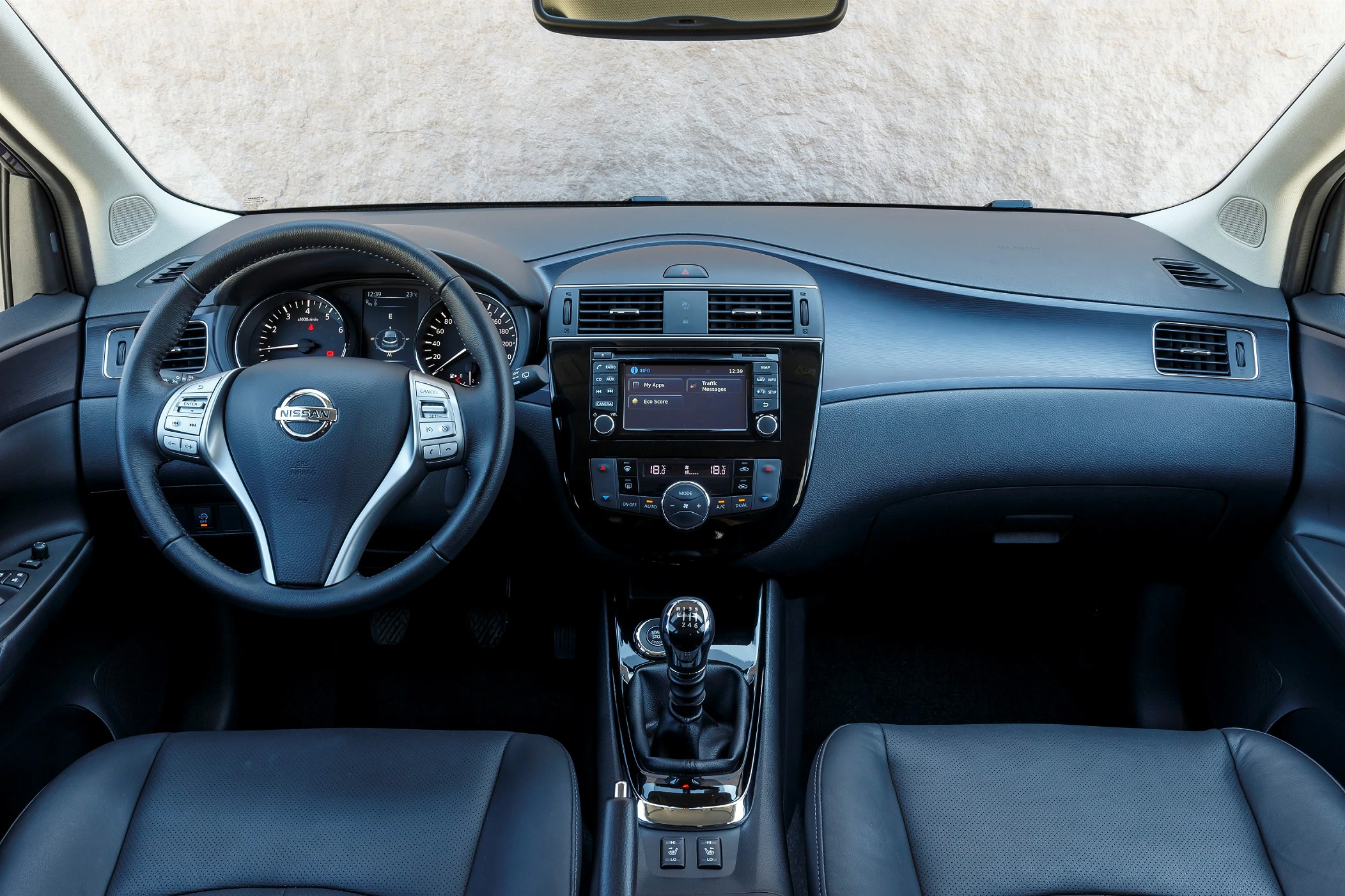 Innenraum eines Autos mit Lederlenkrad, Armaturenbrett mit Touchscreen und manuellem Schaltgetriebe, helles Lederinterieur.