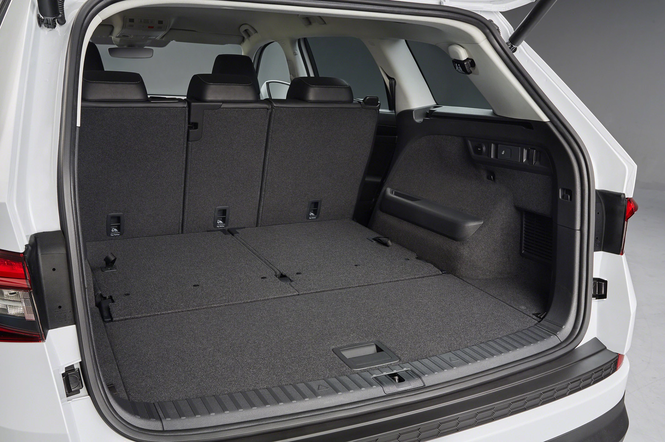 Innenansicht des Kofferraums eines weißen SUV mit umgeklappten Rücksitzen, die eine erweiterte, flache Ladefläche bieten.