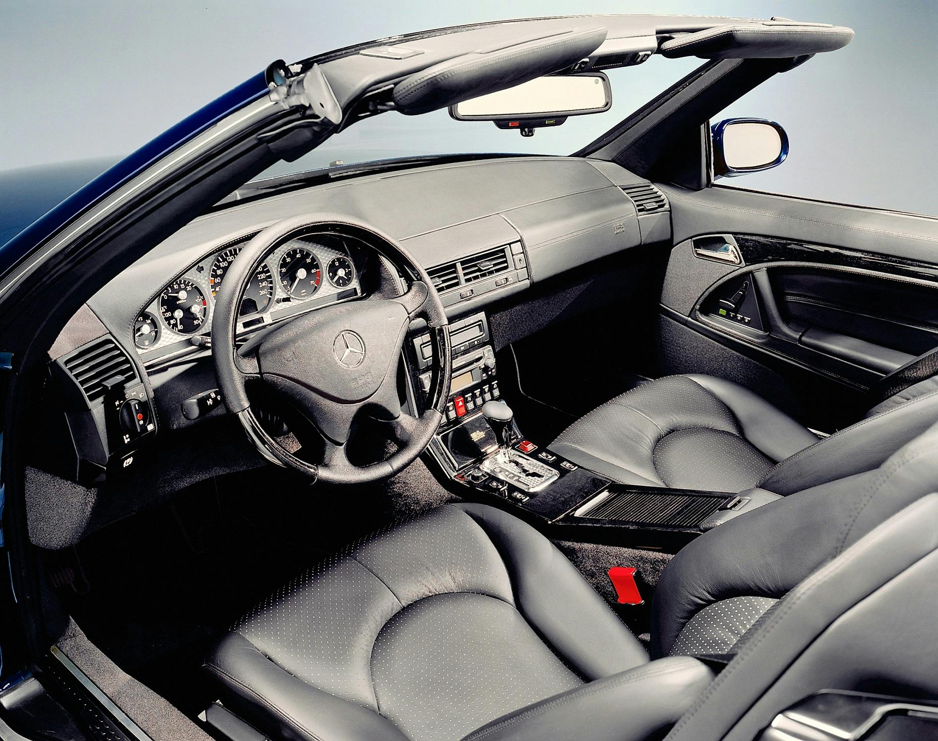 Innenraum eines Mercedes-Benz-Cabrios mit schwarzer Lederausstattung, Holzverkleidung und einem modernen Armaturenbrett mit Rundinstrumenten.