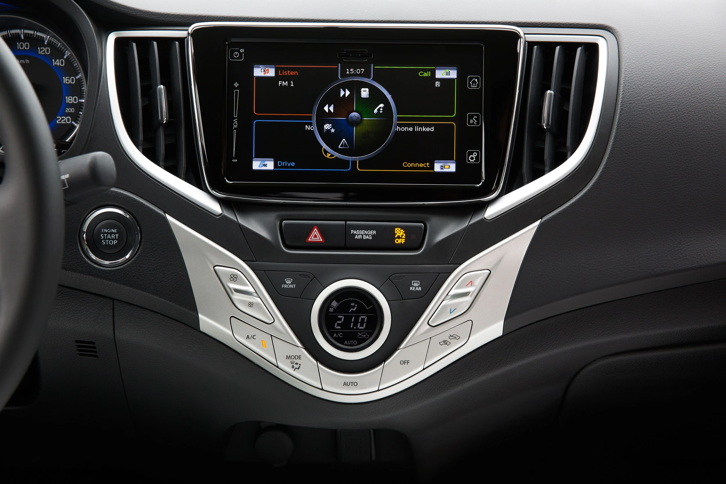 Autoarmaturenbrett mit Touchscreen-Navigationssystem, Klimaanlagenregler und Startknopf. Bildschirm zeigt Musik- und Anrufoptionen.