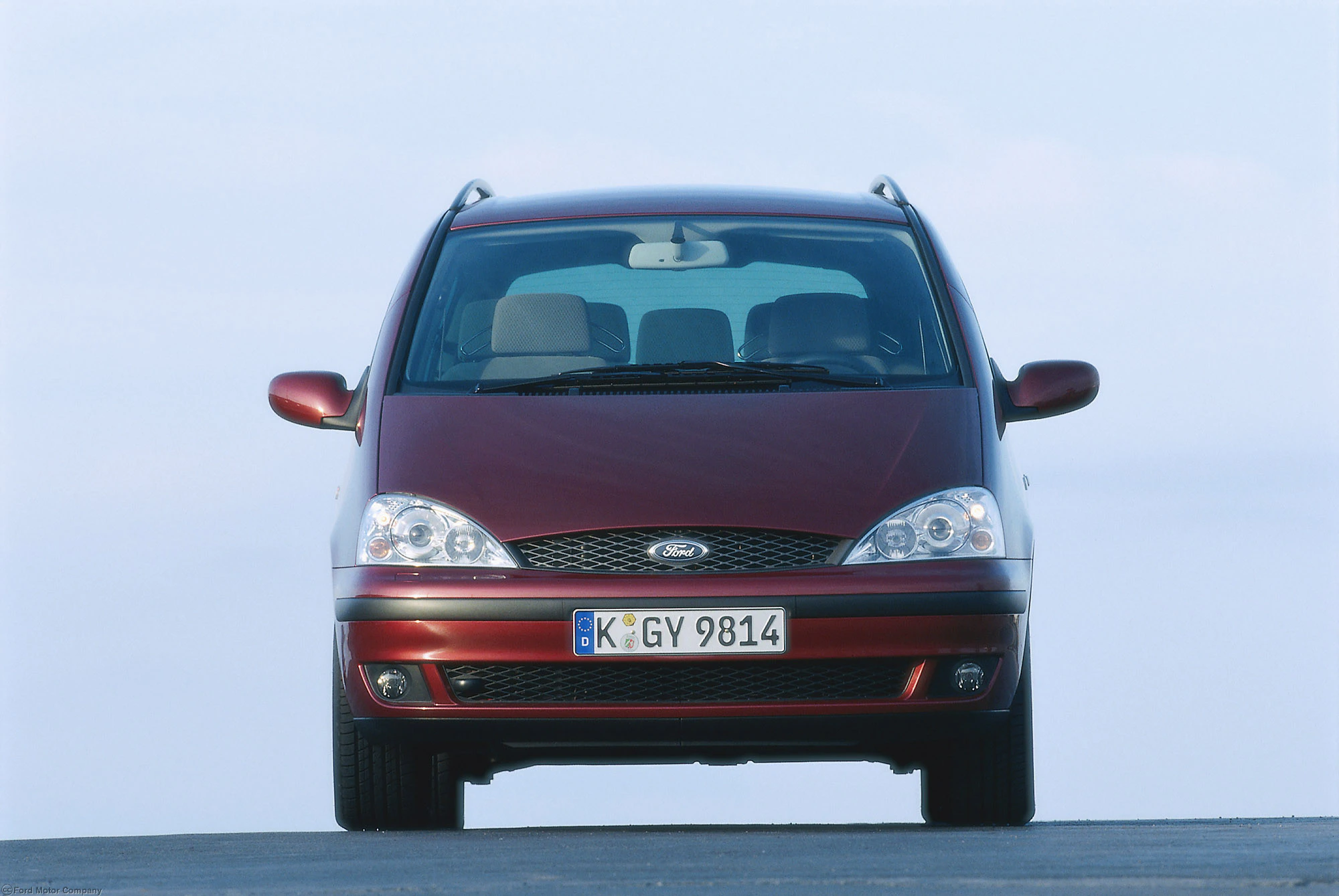 Roter Ford Galaxy van vorne auf einer Straße mit klarem Himmel im Hintergrund.