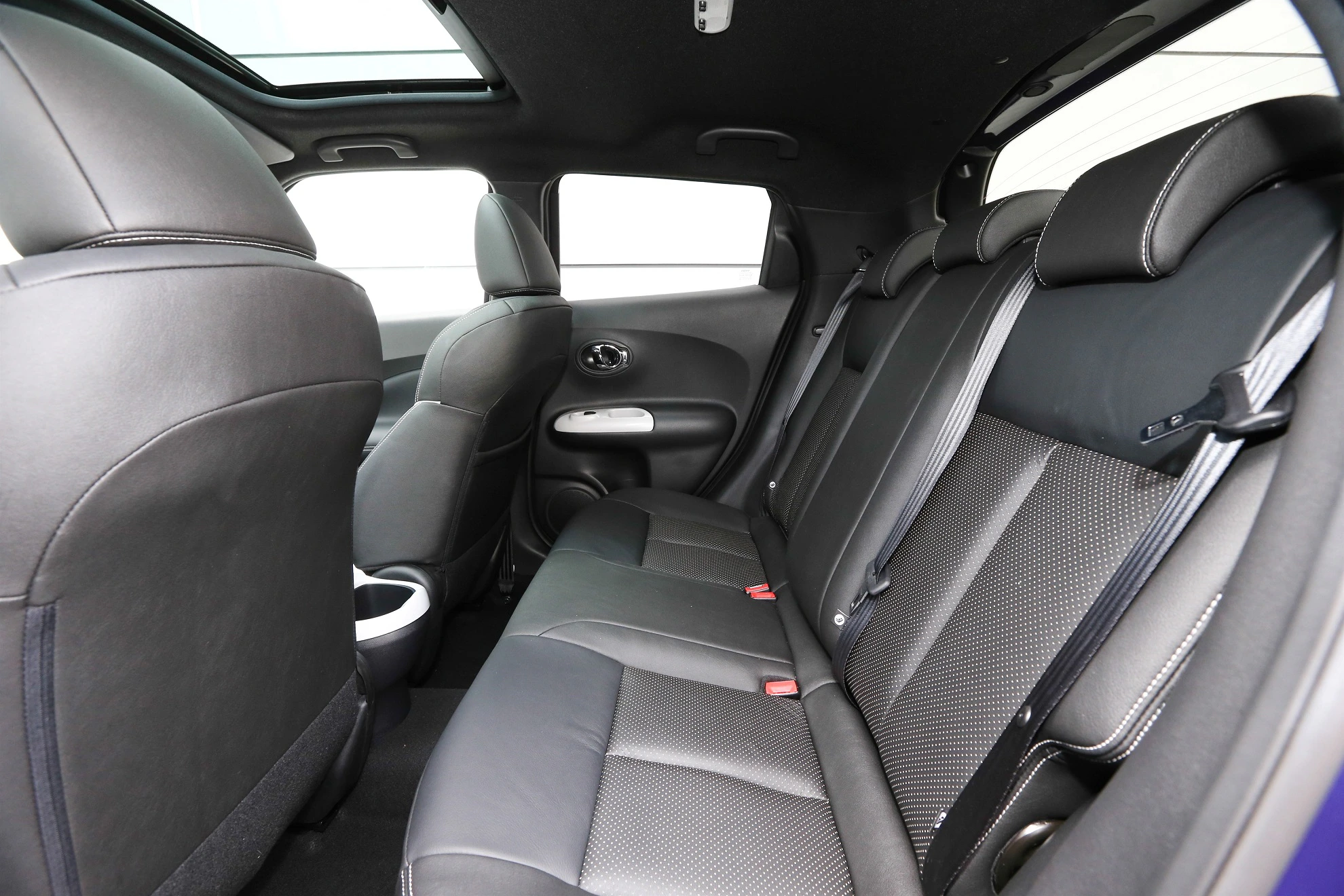Innenansicht eines Autos mit Ledersitzen, Rückbank und Blick auf die hintere Tür. Modernes Design mit Panoramadach.