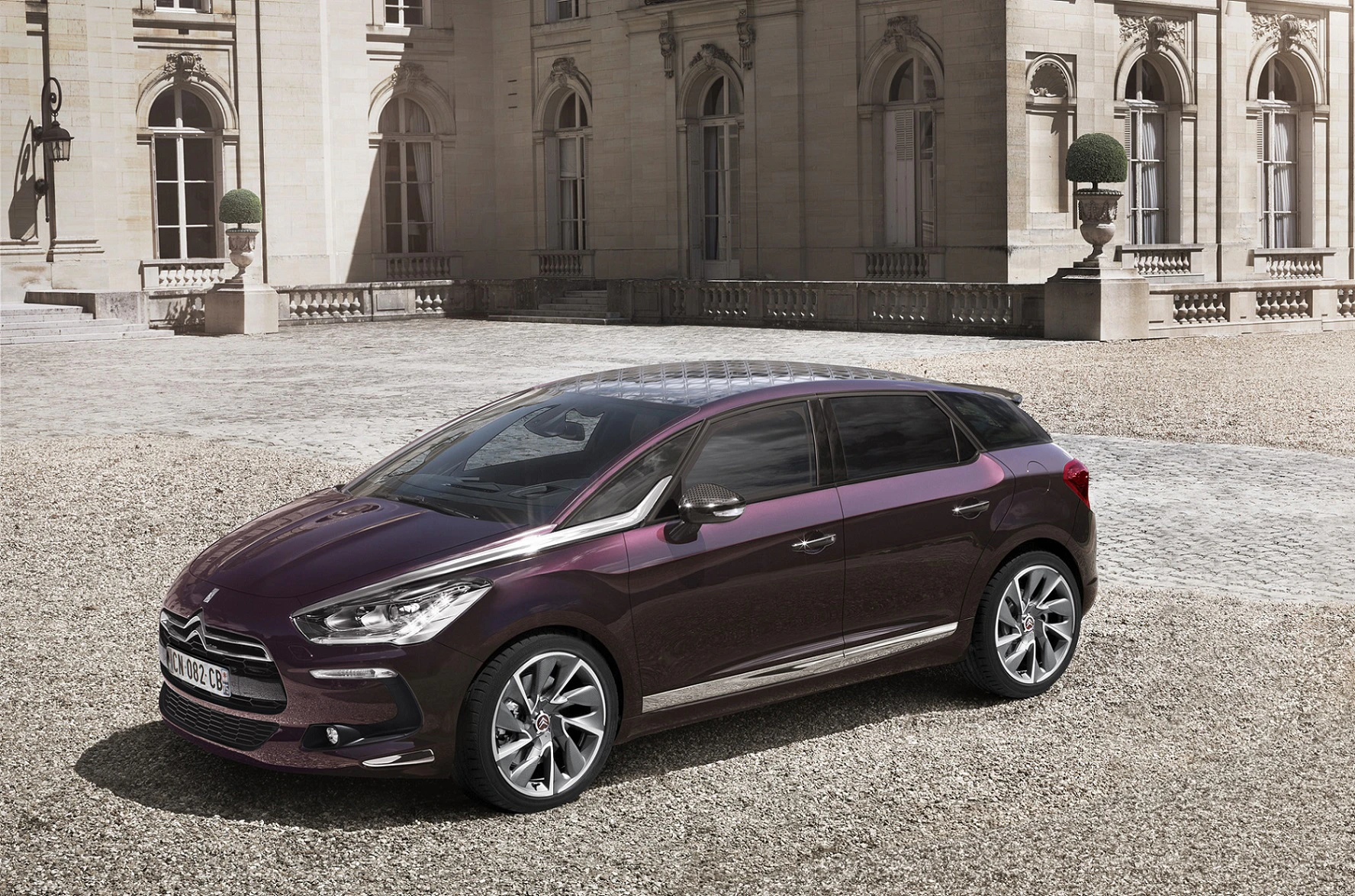 Lila Citroën DS5 steht vor einem historischen Gebäude mit Steinpflaster, elegante Architektur im Hintergrund.