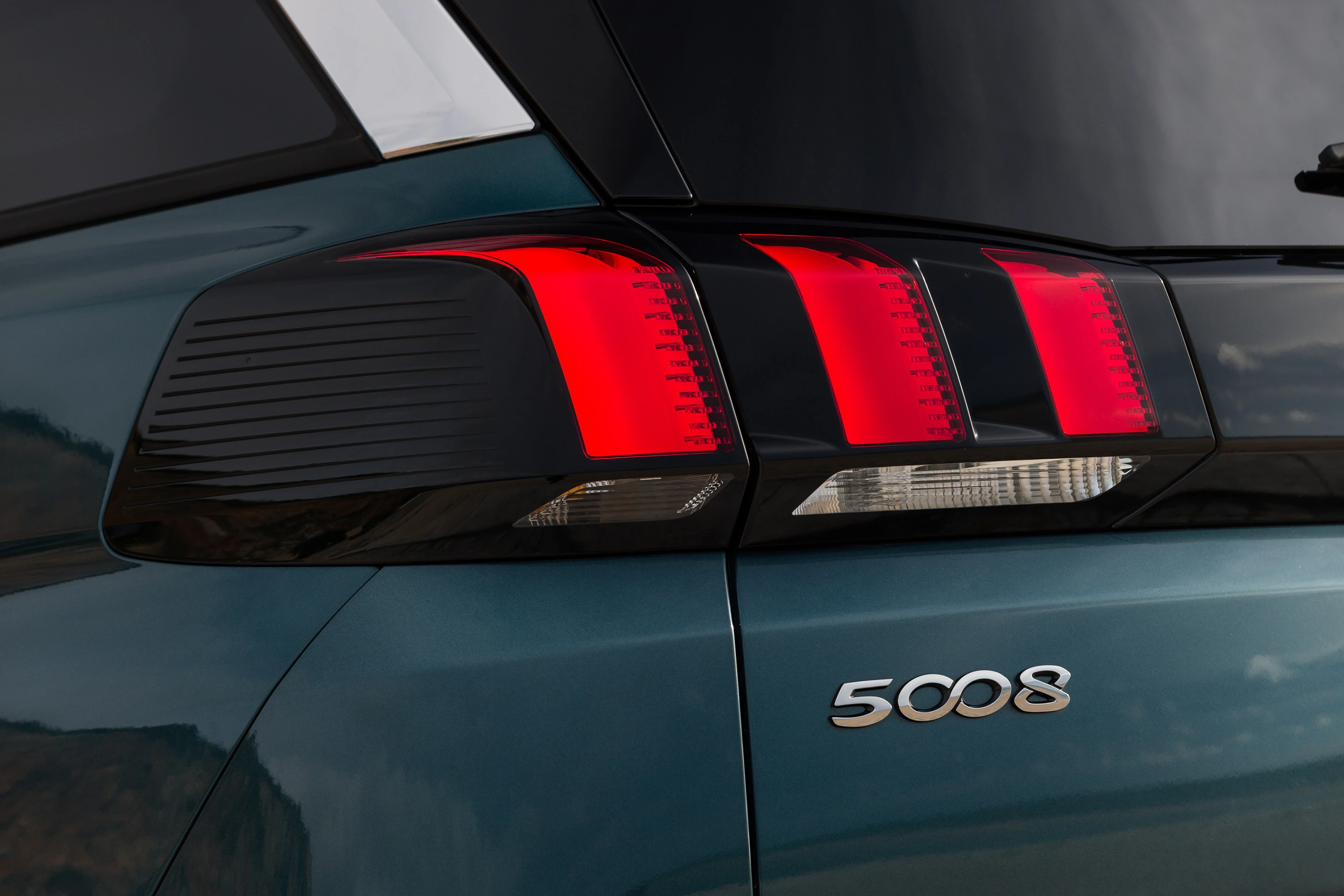 Nahaufnahme eines dunkelblauen Autos mit sichtbarem Rücklicht und dem Emblem "5008" auf der Rückseite.