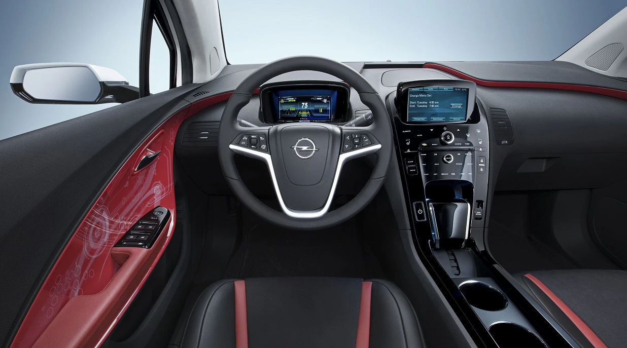 Innenraum eines Autos mit modernem Design, rotem Innenverkleidungselement, Multifunktionslenkrad und großem Touchscreen-Display in der Mittelkonsole.