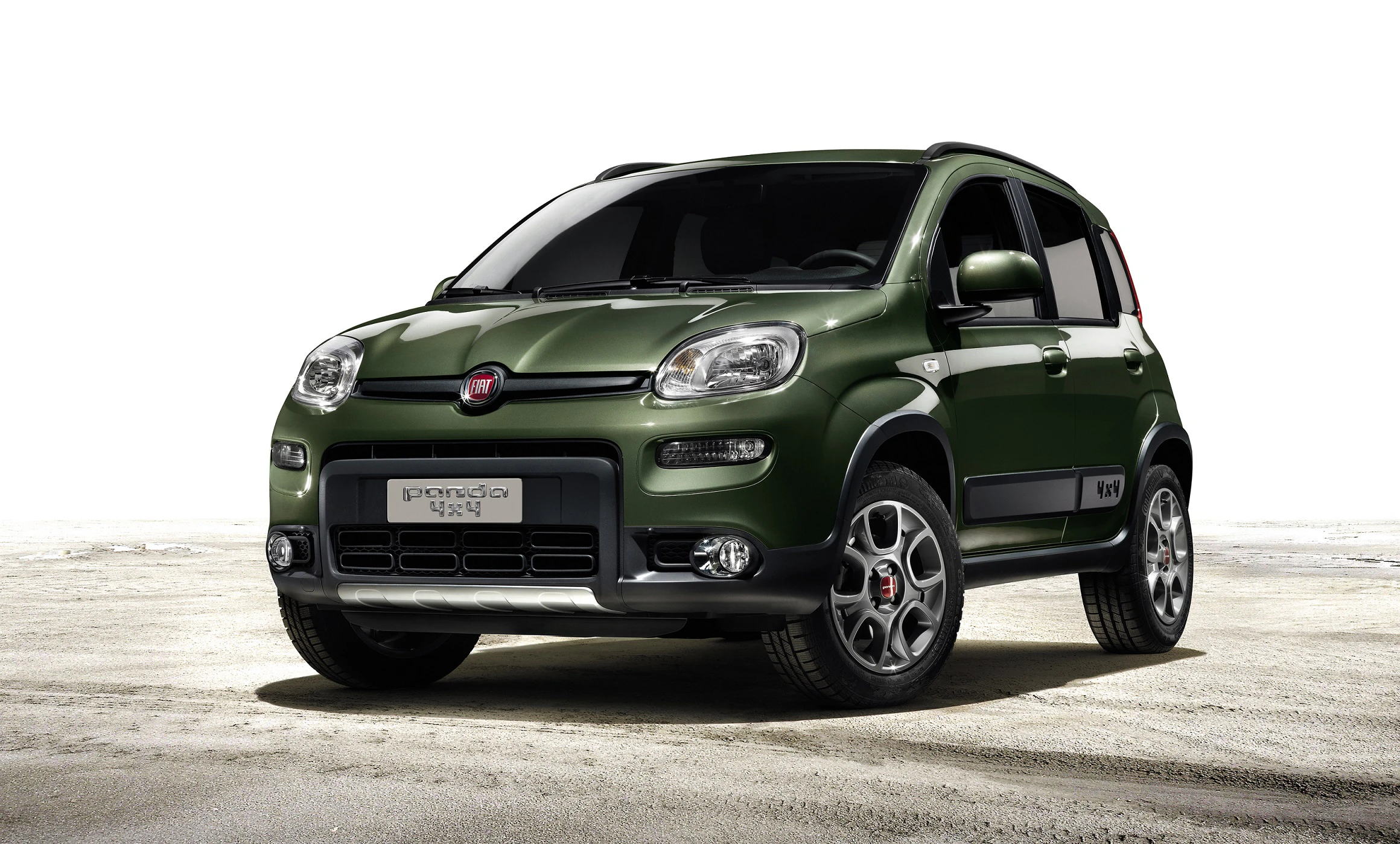 Grüner Fiat Panda 4x4 auf sandigem Untergrund vor weißem Hintergrund, Seitenansicht, beleuchtete Scheinwerfer.