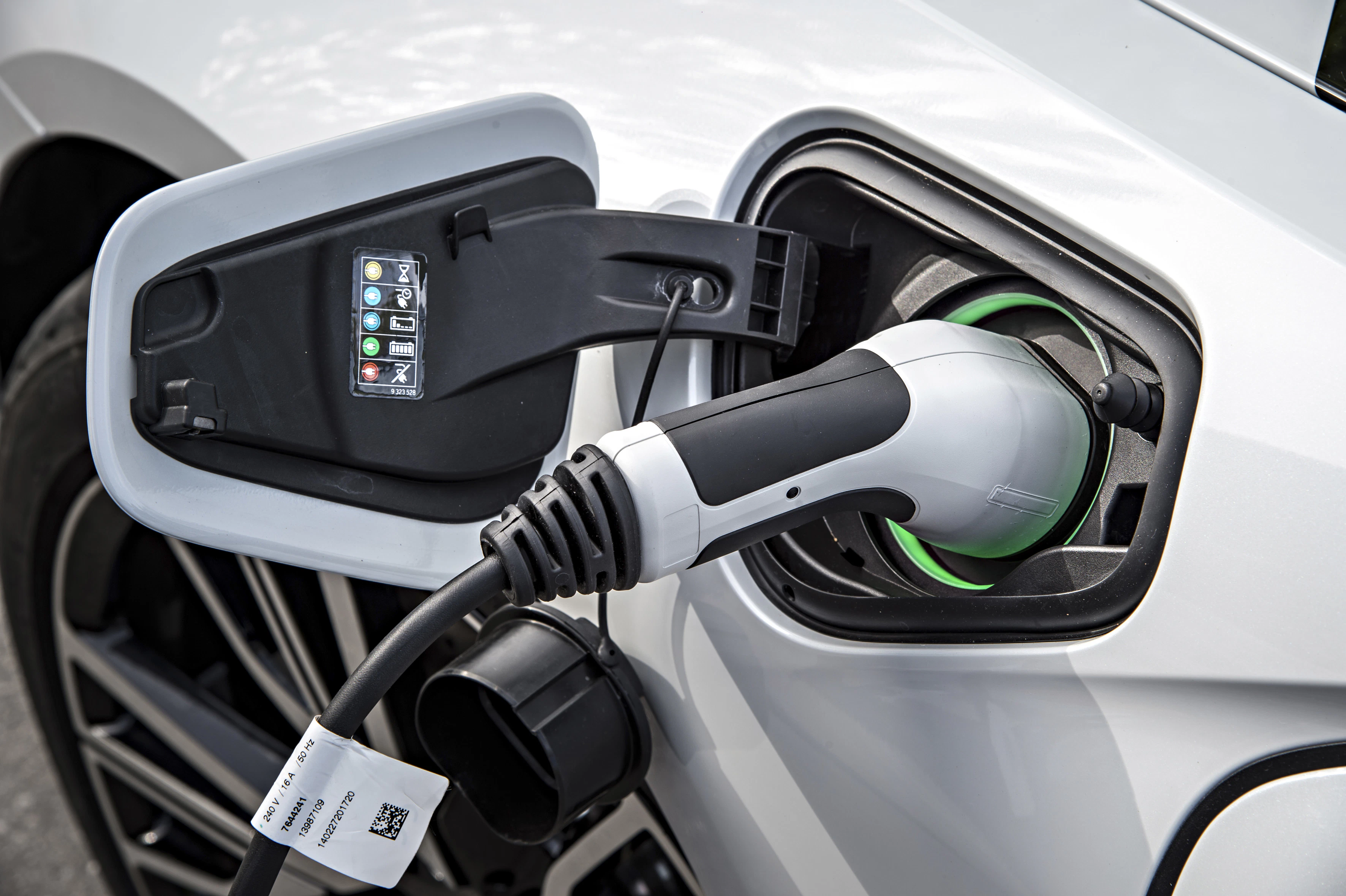Elektroauto wird geladen: Der Ladestecker ist mit dem Ladeanschluss eines weißen Fahrzeugs verbunden.