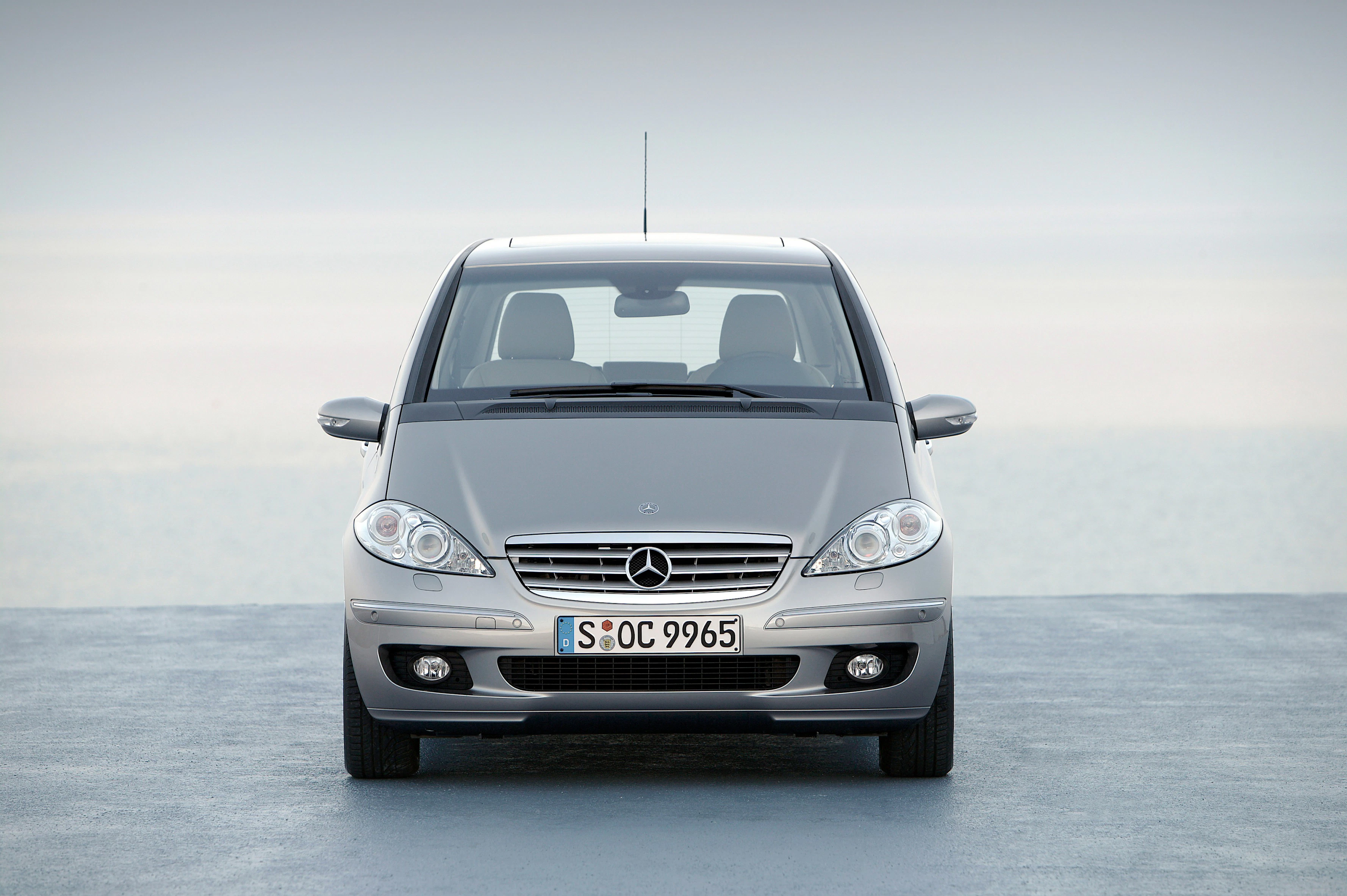 Silberner Mercedes-Benz A-Klasse steht auf einem Asphaltboden, fotografiert von vorne, mit einem minimalistischen Hintergrund.
