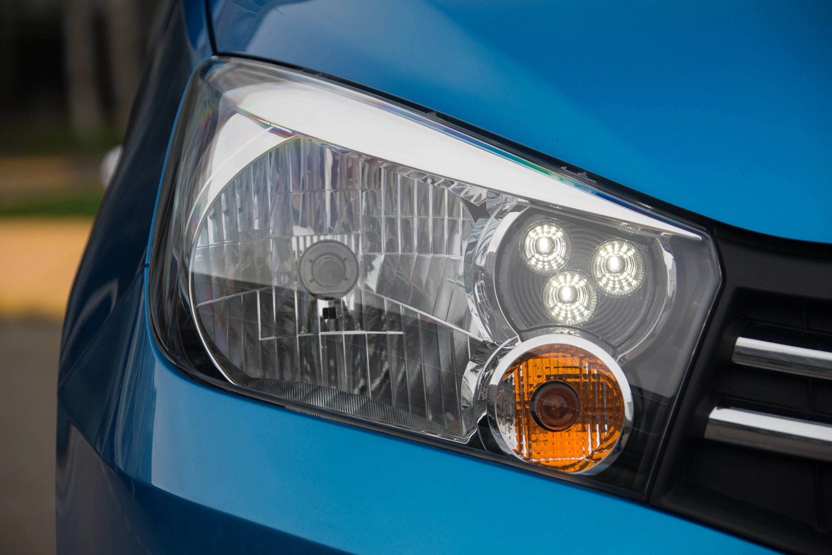 Nahaufnahme eines blauen Auto-Scheinwerfers mit asymmetrischen Lichtern und klarem Glasdesign.