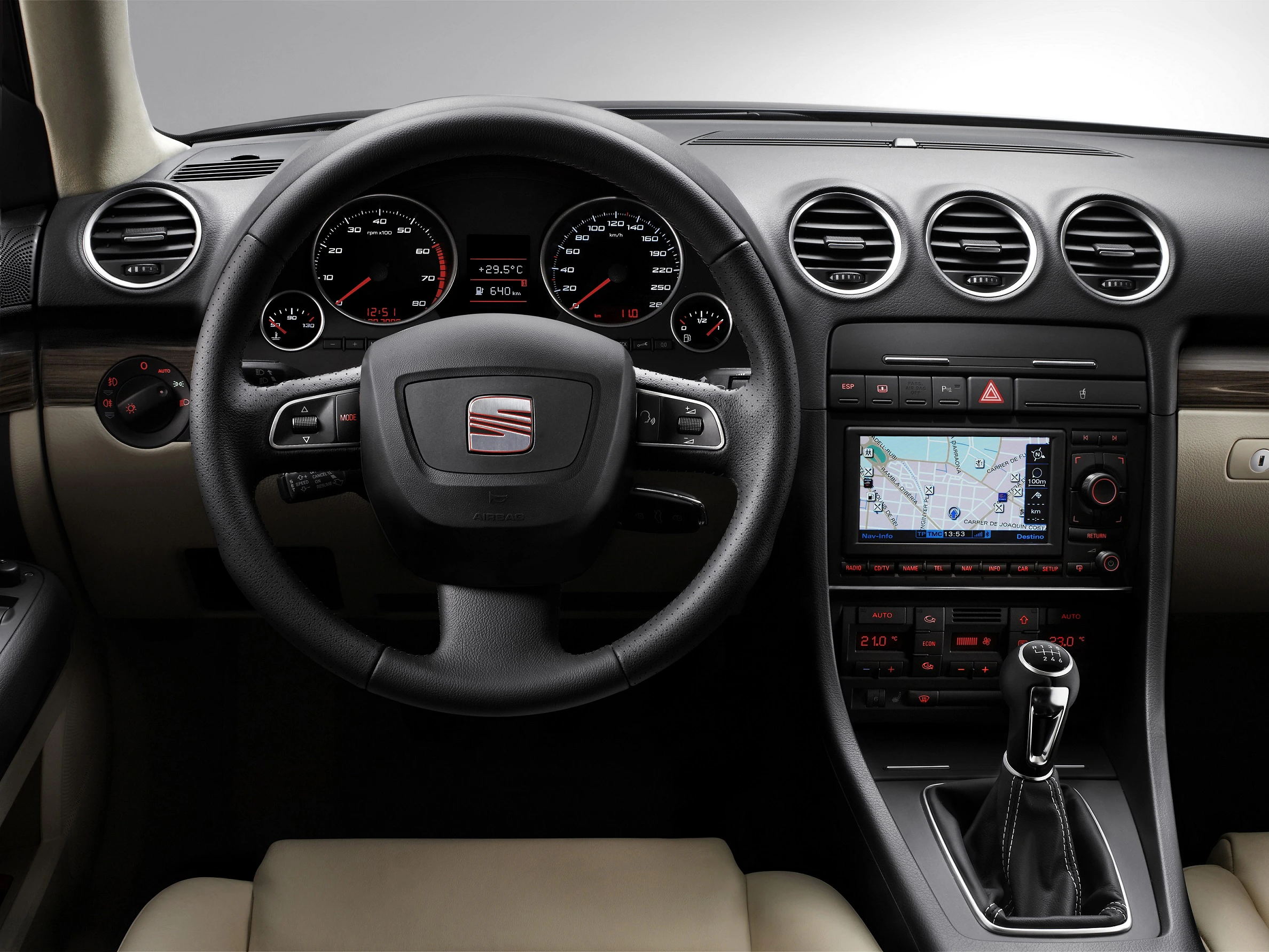 Lenkrad und Armaturenbrett eines Autos mit integriertem Navigationssystem. Anzeigeinstrumente und Schalthebel sind sichtbar.