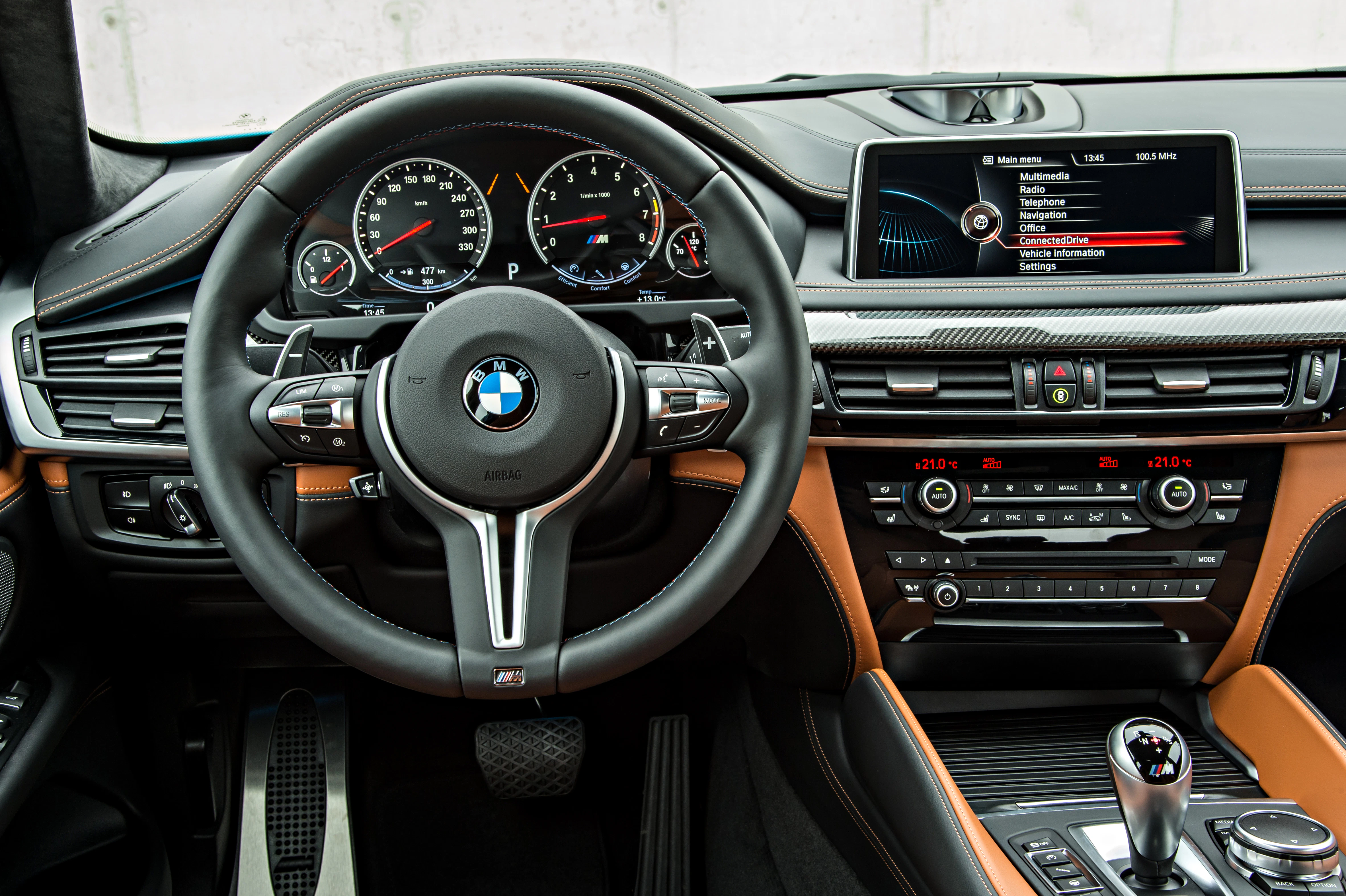 Innenraum eines BMWs mit Lederdetails, Multifunktionslenkrad, modernem Armaturenbrett, Touchscreen und Automatikschaltung.