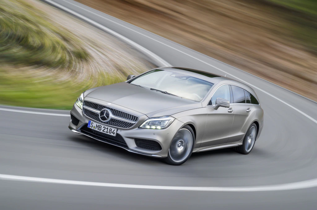 Mercedes-Benz auf kurviger Straße, dynamische Bewegung. Silbernes Fahrzeug, elegante Linien, verschwommener Hintergrund zeigt Geschwindigkeit.