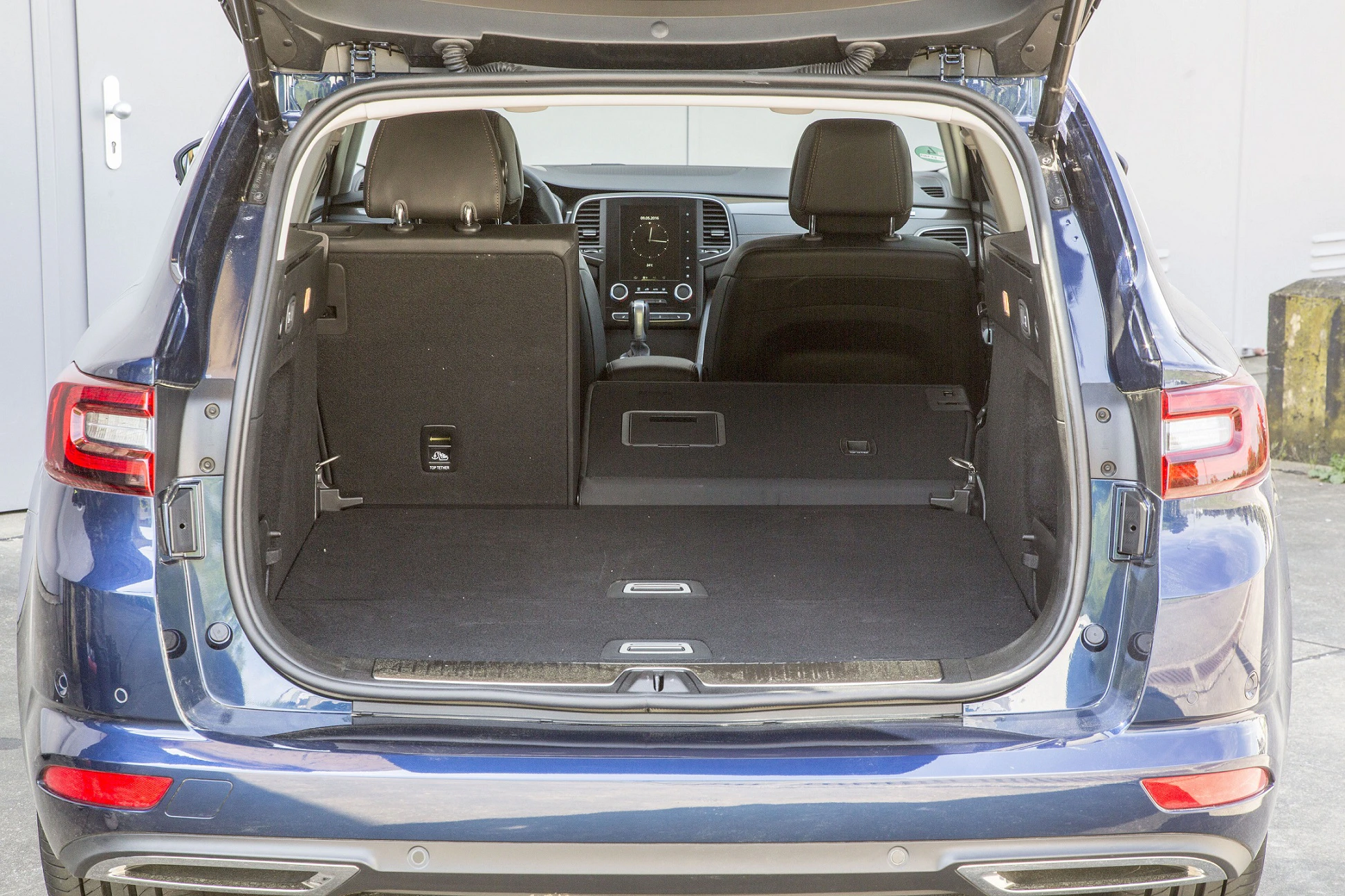 Offener Kofferraum eines blauen SUVs, eine Rücksitzlehne ist umgeklappt, zeigt großzügigen Stauraum und modernes Innenraumdesign.
