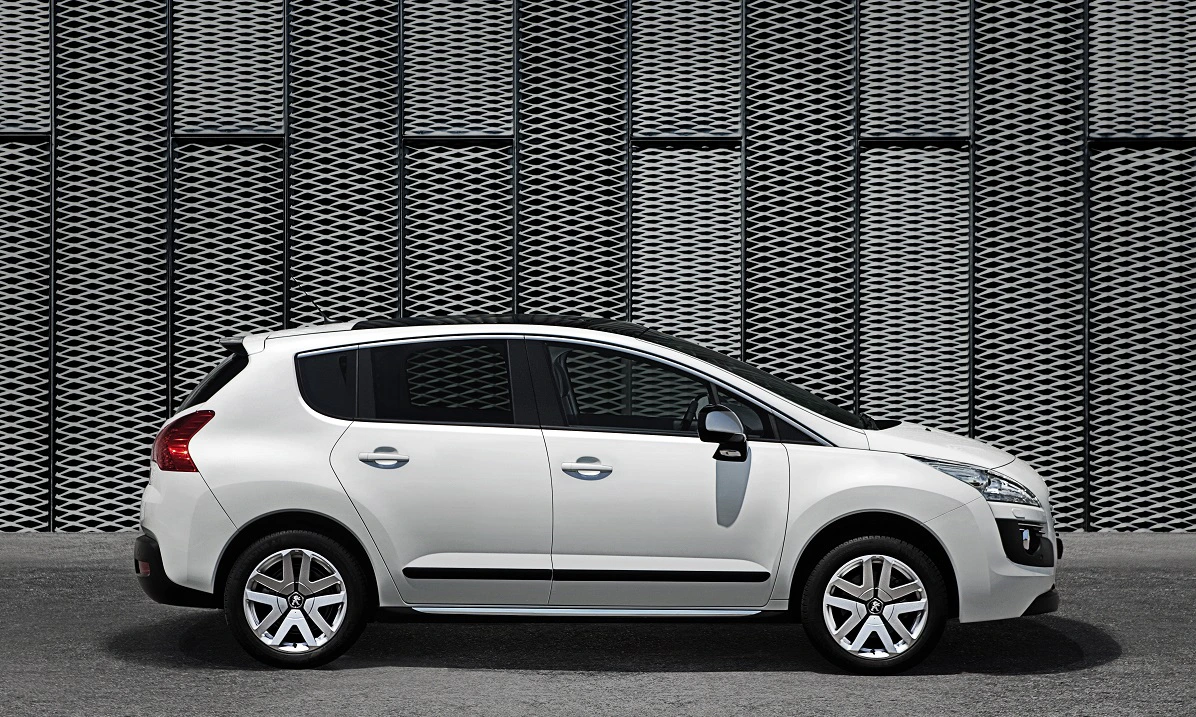 Weißer SUV geparkt seitlich vor einer Wand mit geometrischem Muster.