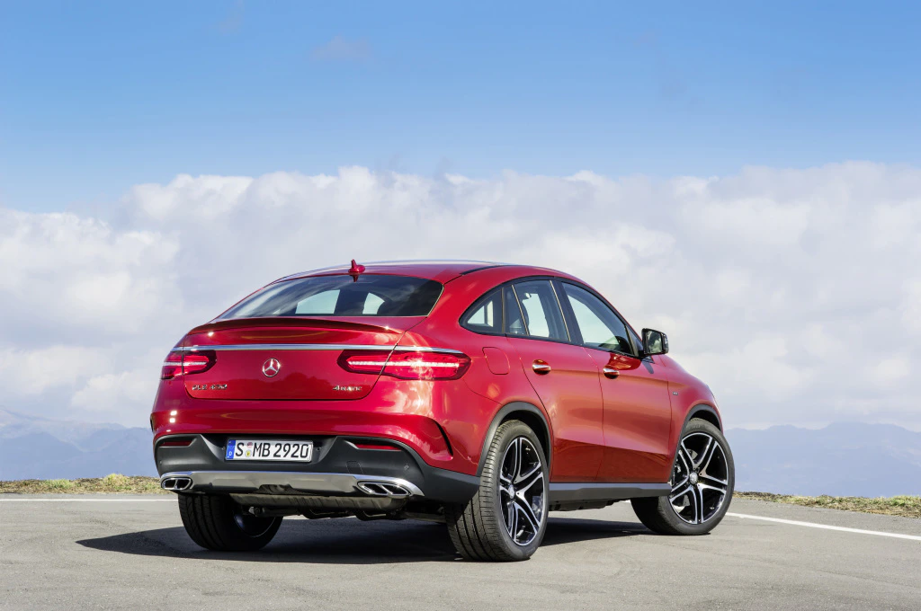 Ein roter Mercedes-Benz SUV steht auf einer Straße vor bewölktem Himmel. Das Auto zeigt die Rückansicht mit markanten Heckleuchten.