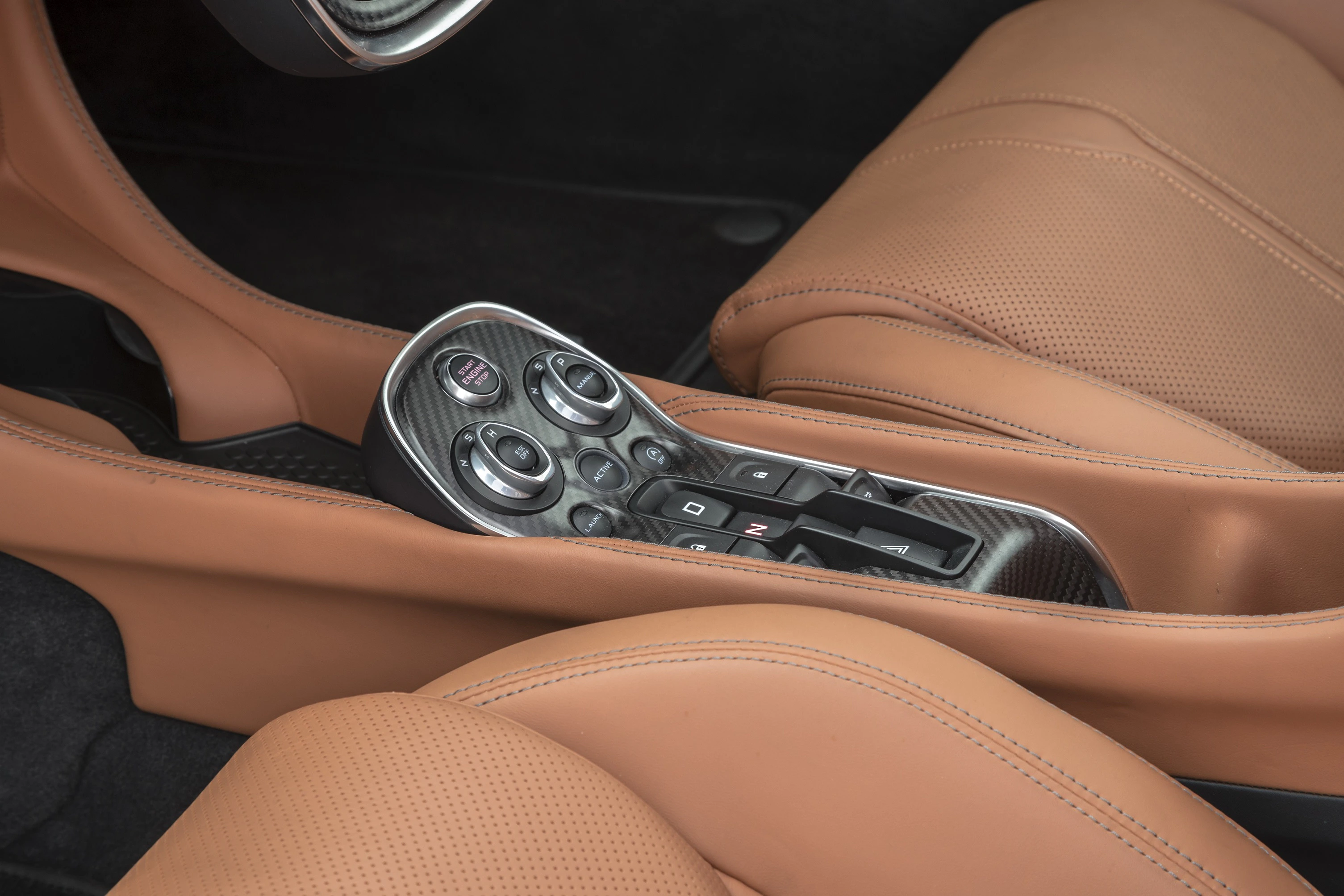 Nahaufnahme einer Luxus-Autokonsole mit Lederpolsterung und elegantem Gangschaltknauf, umgeben von braunem Leder im Innenraum.