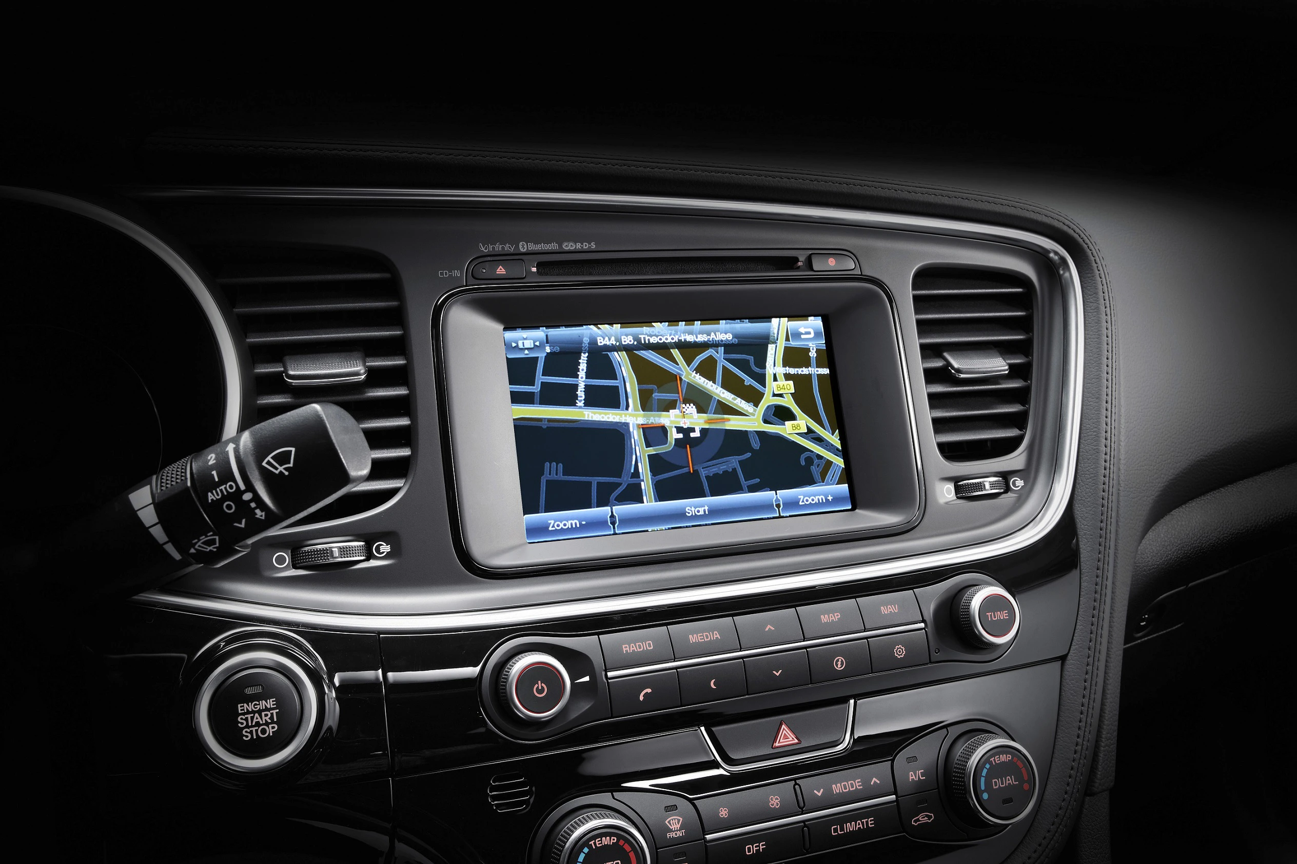 Navigationssystem im Auto mit Straße auf dem Bildschirm. Umgeben von Lüftungsschlitzen und Bedienelementen.