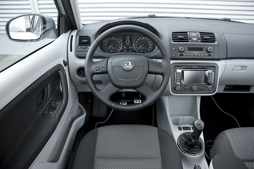 Innenraum eines Autos mit Lenkrad, Armaturenbrett, Armaturen und Schaltknüppel. Modernes Design mit grauer Polsterung.