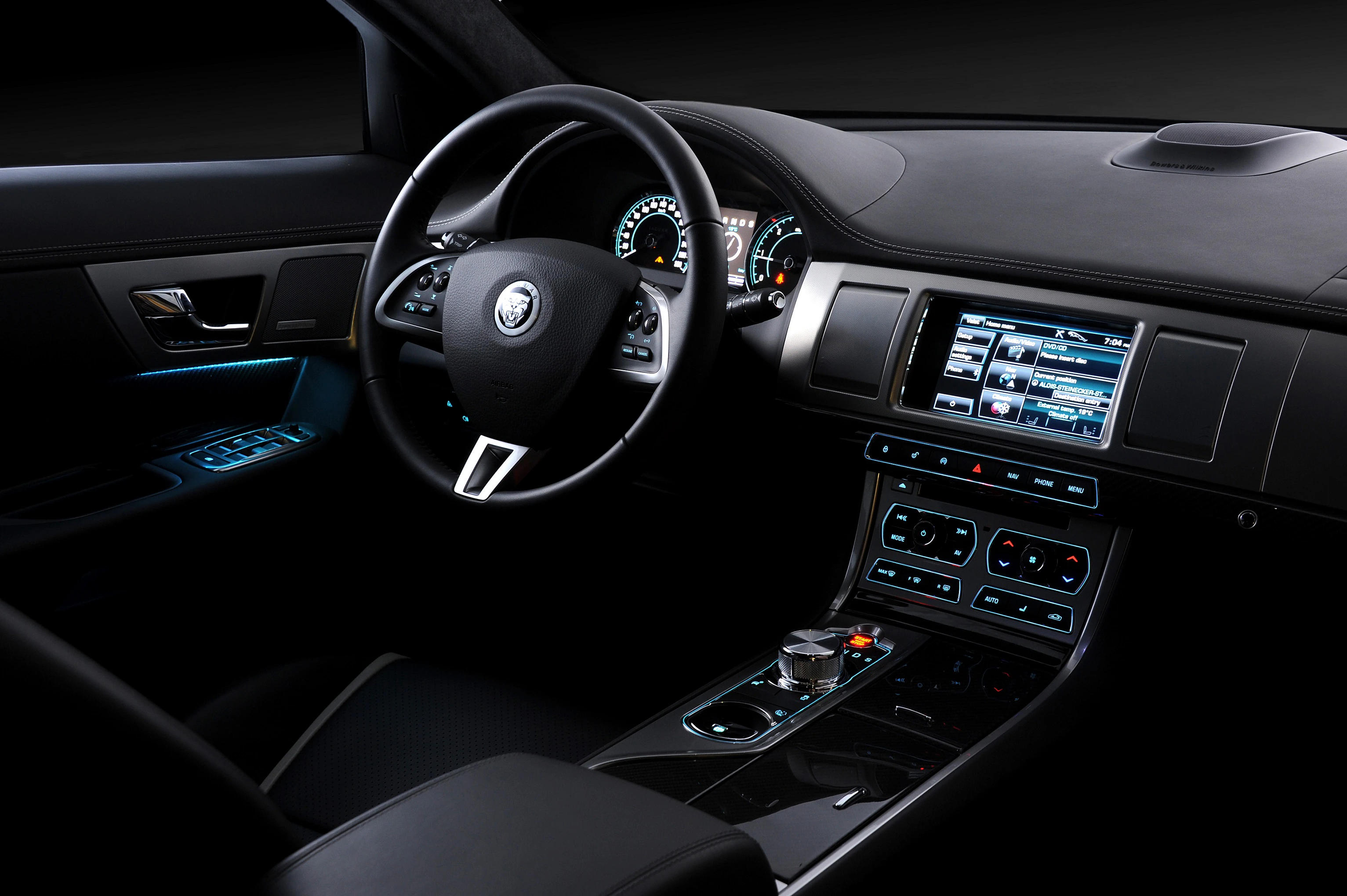 Luxuriöser Autoinnenraum mit modernem Lenkrad, Armaturenbrett und Touchscreen; dunkle Lederpolsterung und dezente Beleuchtung.