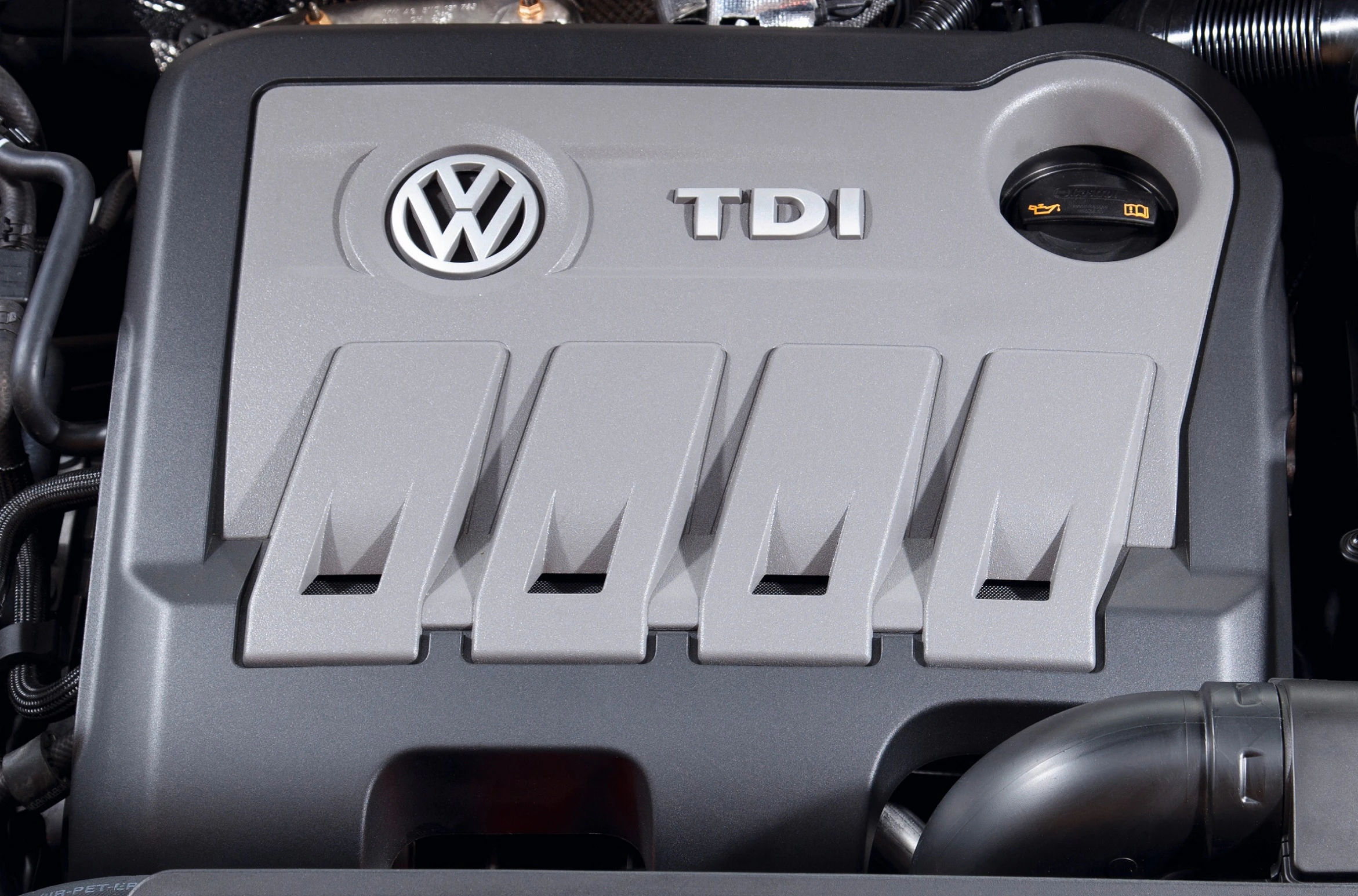 Nahaufnahme eines VW TDI-Motors mit Öldeckel auf der rechten Seite. Logo und Schriftzug deutlich sichtbar.