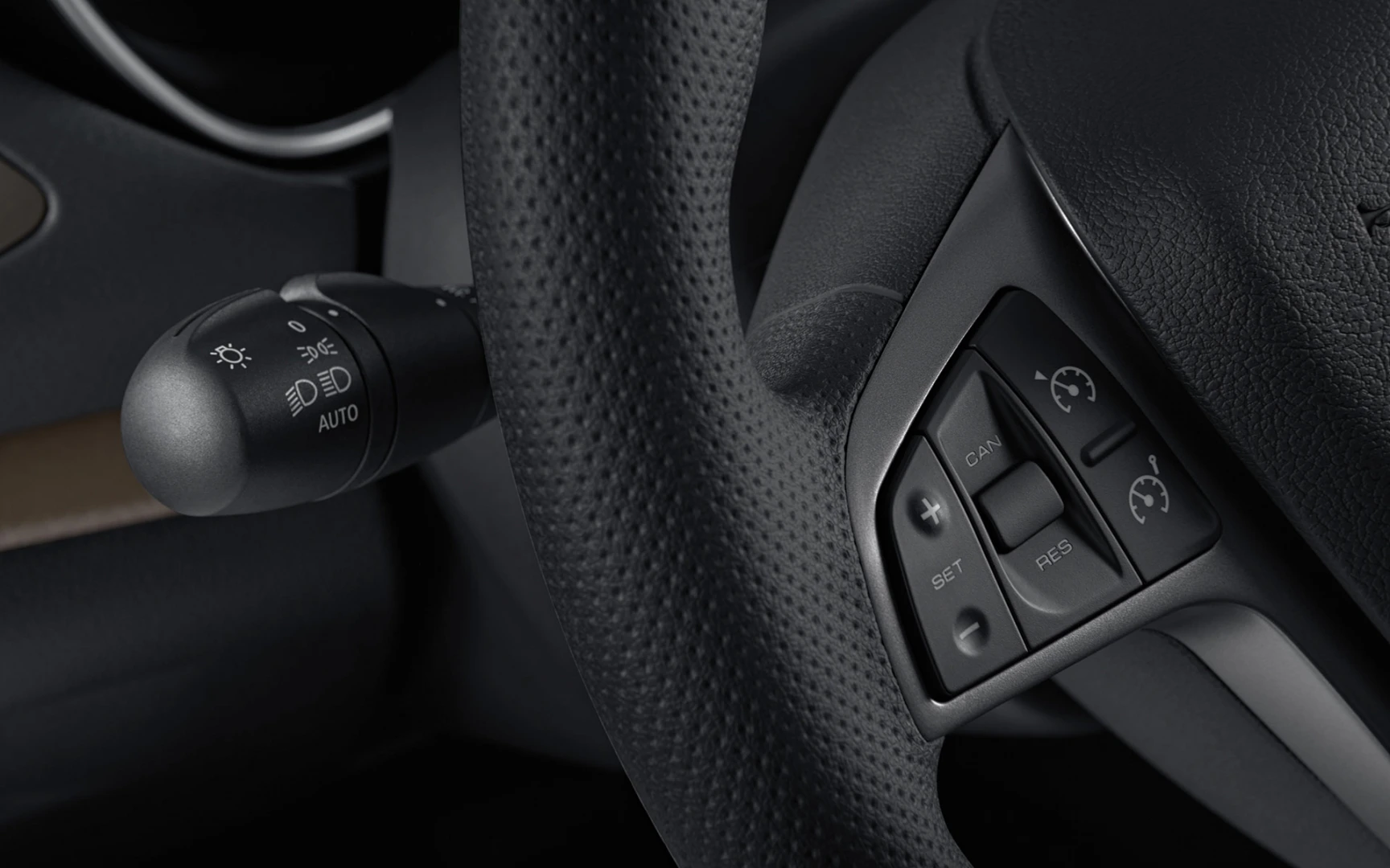 Nahaufnahme eines Lenkrads mit Bedienelementen für Tempomat, Licht und Blinker in einem Auto.