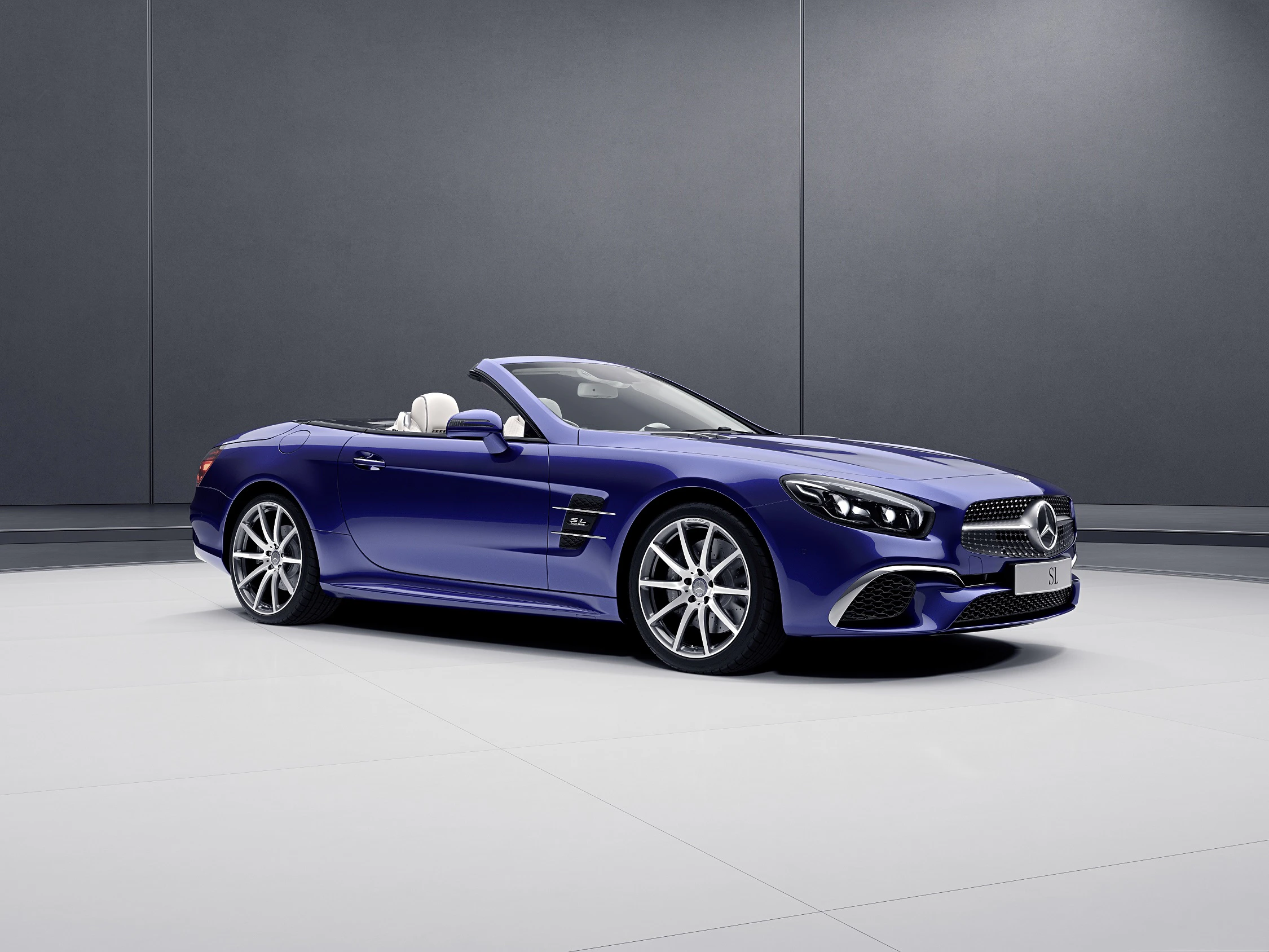 Blaues Cabriolet mit offenem Verdeck und sportlicher Karosserie in einem modernen, hellen Showroom.