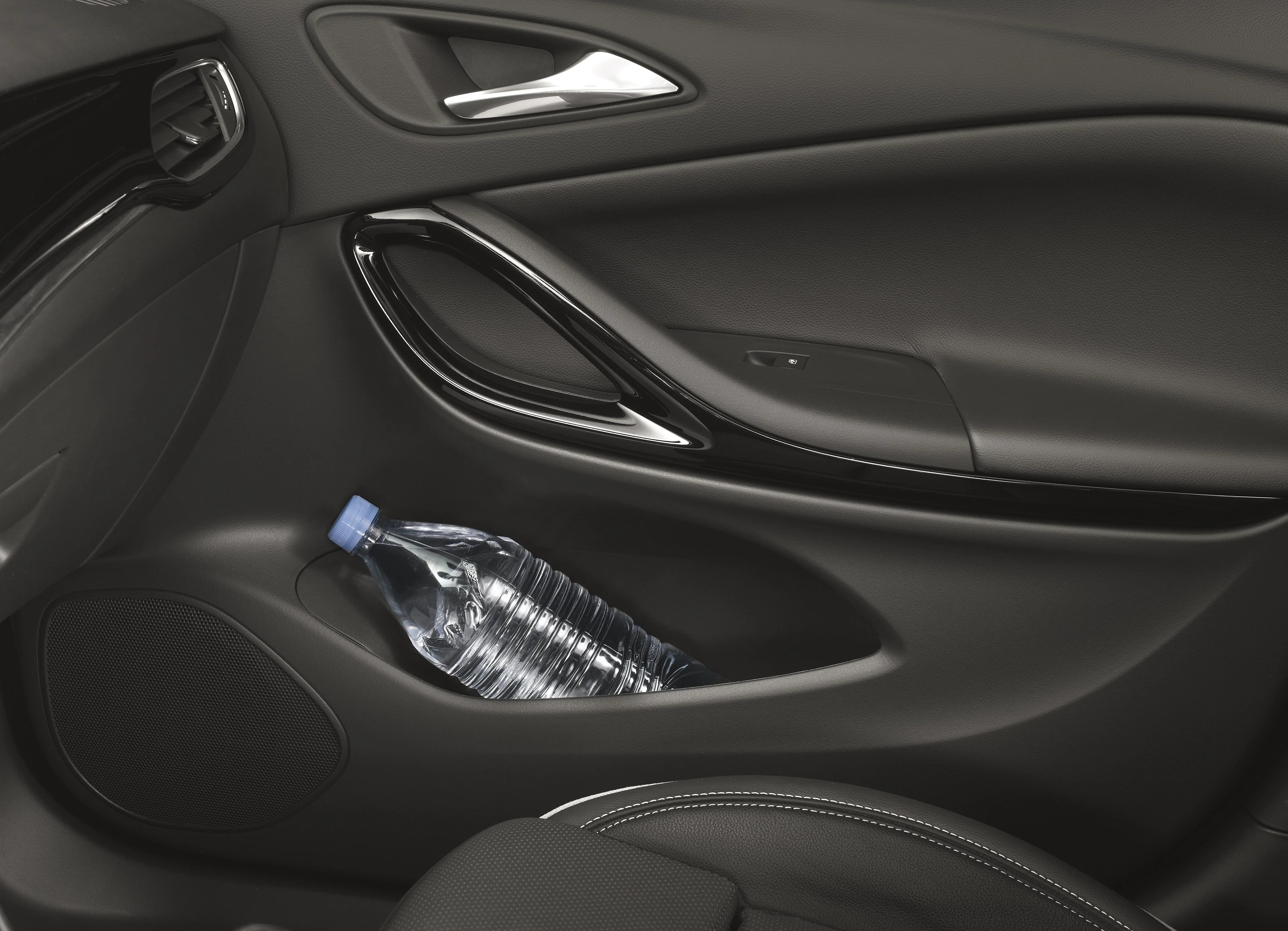 Wasserflasche in der Türablage eines Autos, umgeben von schwarzen Türverkleidungen und silbernen Akzenten.