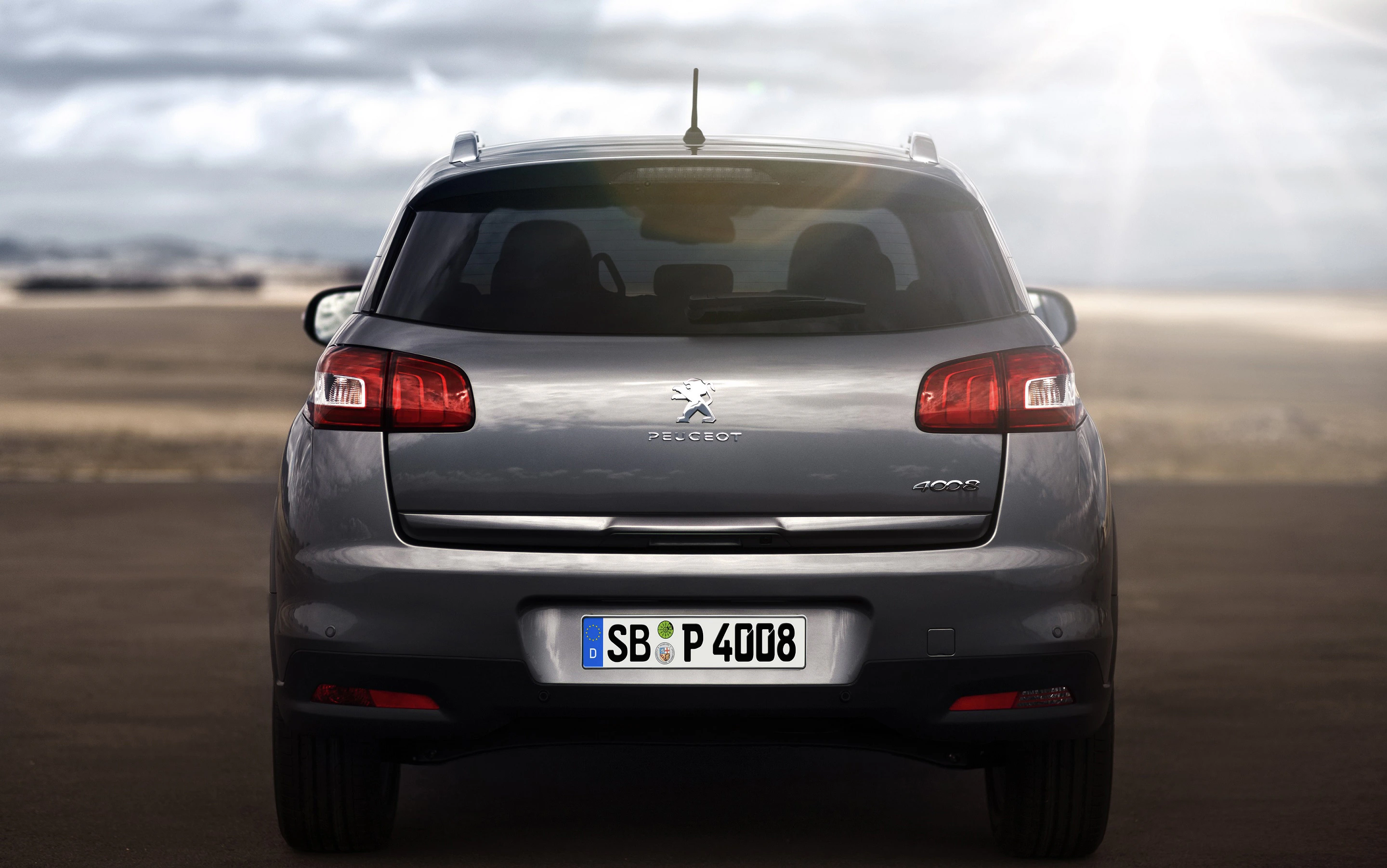 Rückansicht eines grauen Peugeot 4008 SUV auf einer Straße, beleuchtet von Sonnenschein, mit Kennzeichen SB P 4008.