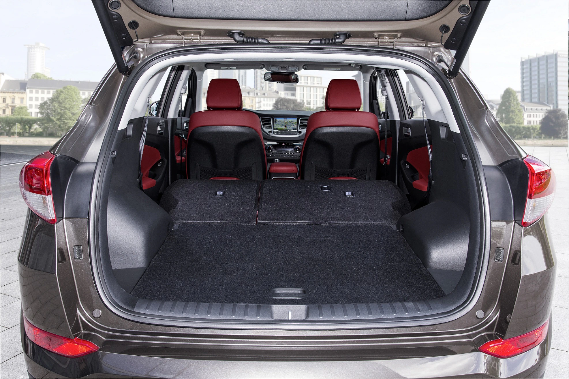 Rückansicht eines SUVs mit geöffnetem Kofferraum. Die Sitze sind umgeklappt, was einen großen Laderaum mit roten Vordersitzen zeigt.