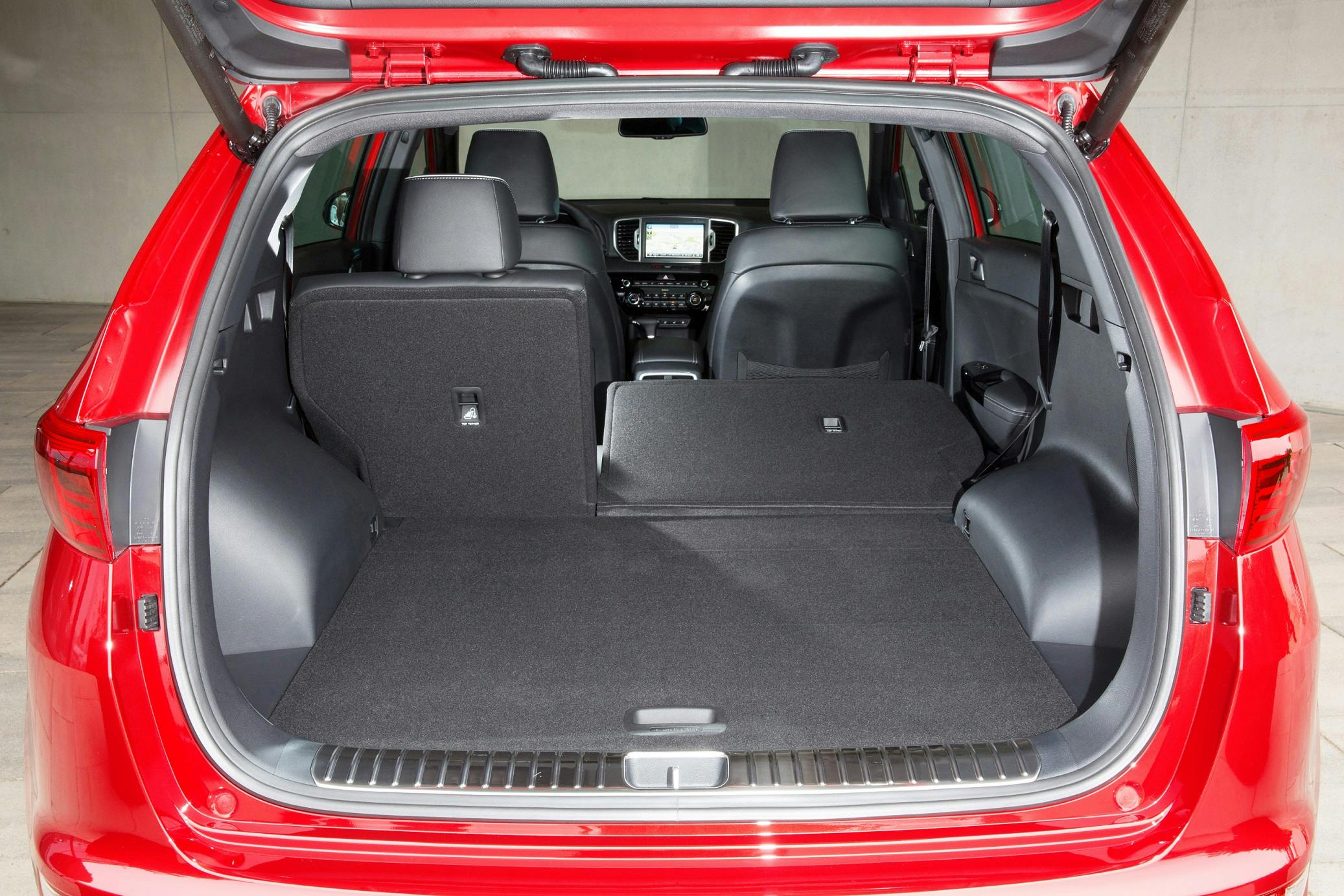 Roter SUV mit offenem Kofferraum, eine Rücksitzbank ist umgeklappt, große Ladefläche, moderner Innenraum mit sichtbarem Bildschirm.