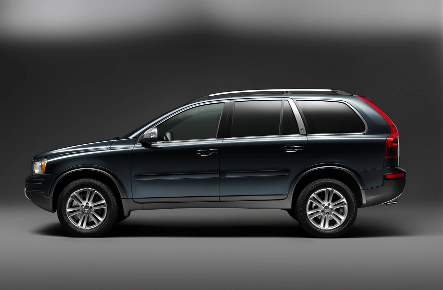 Dunkelgrüner SUV im Profil vor schwarzem Hintergrund, mit silbernen Felgen und getönten Scheiben.