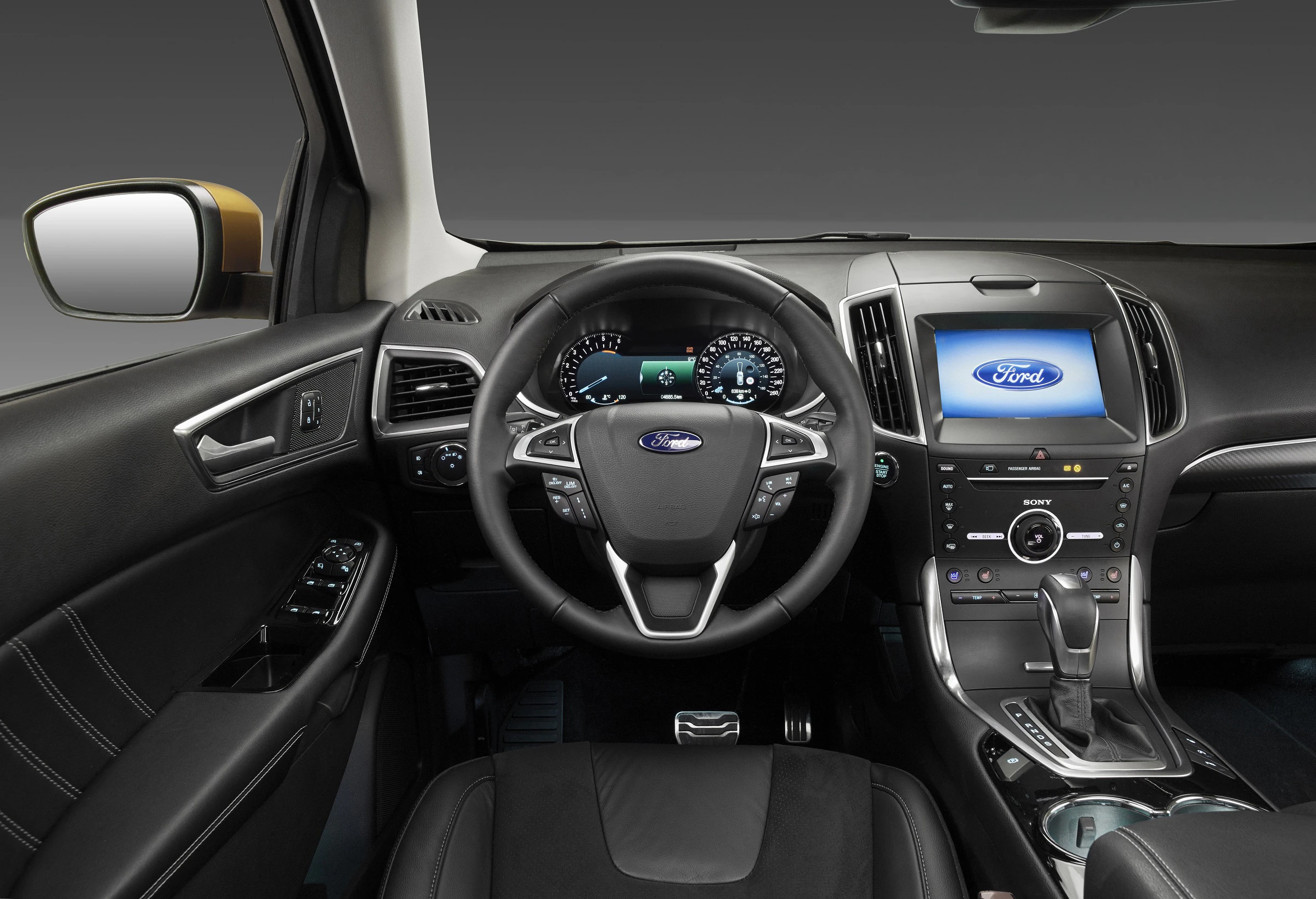 Innenraum eines Ford-Autos mit Lenkrad, Armaturenbrett und Touchscreen-Display. Die Anzeige leuchtet und zeigt das Ford-Logo.