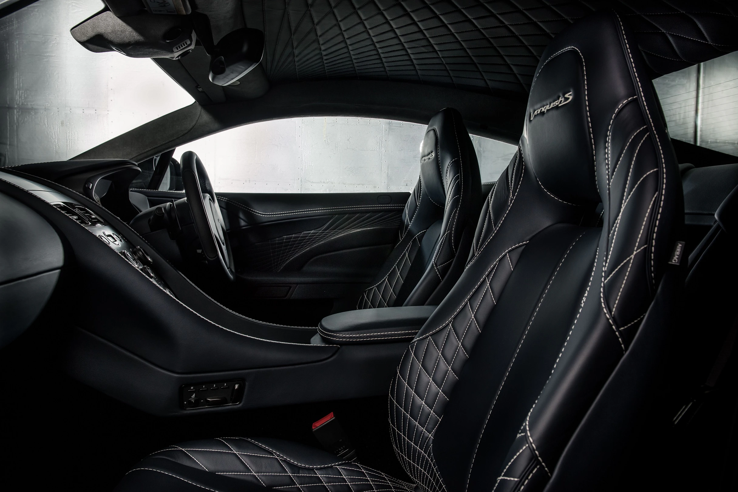Innenraum eines Luxusautos mit schwarzen Ledersitzen und weißen Nähten. Moderner, eleganter Stil mit durchdachtem Design.