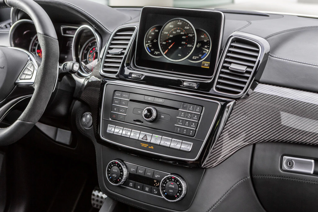 Nahaufnahme eines modernen Auto-Armaturenbretts mit Touchscreen-Display, Lüftungsschlitzen und Bedienknöpfen in einem luxuriösen Interieurdesign.