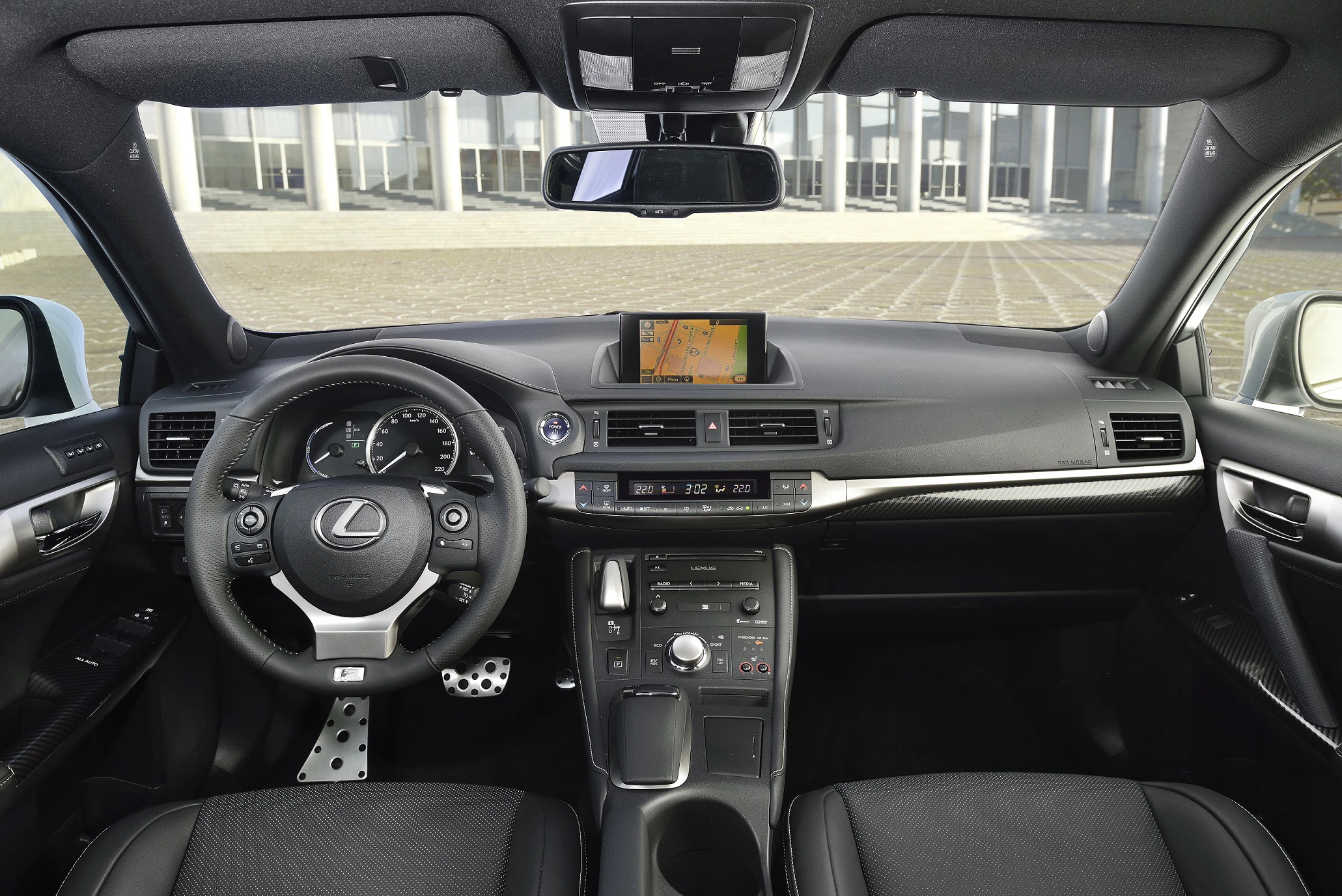 Innenraum eines Autos mit Lederlenkrad, Armaturenbrett und Navigationsbildschirm. Moderner, eleganter Look mit schwarzen Akzenten.