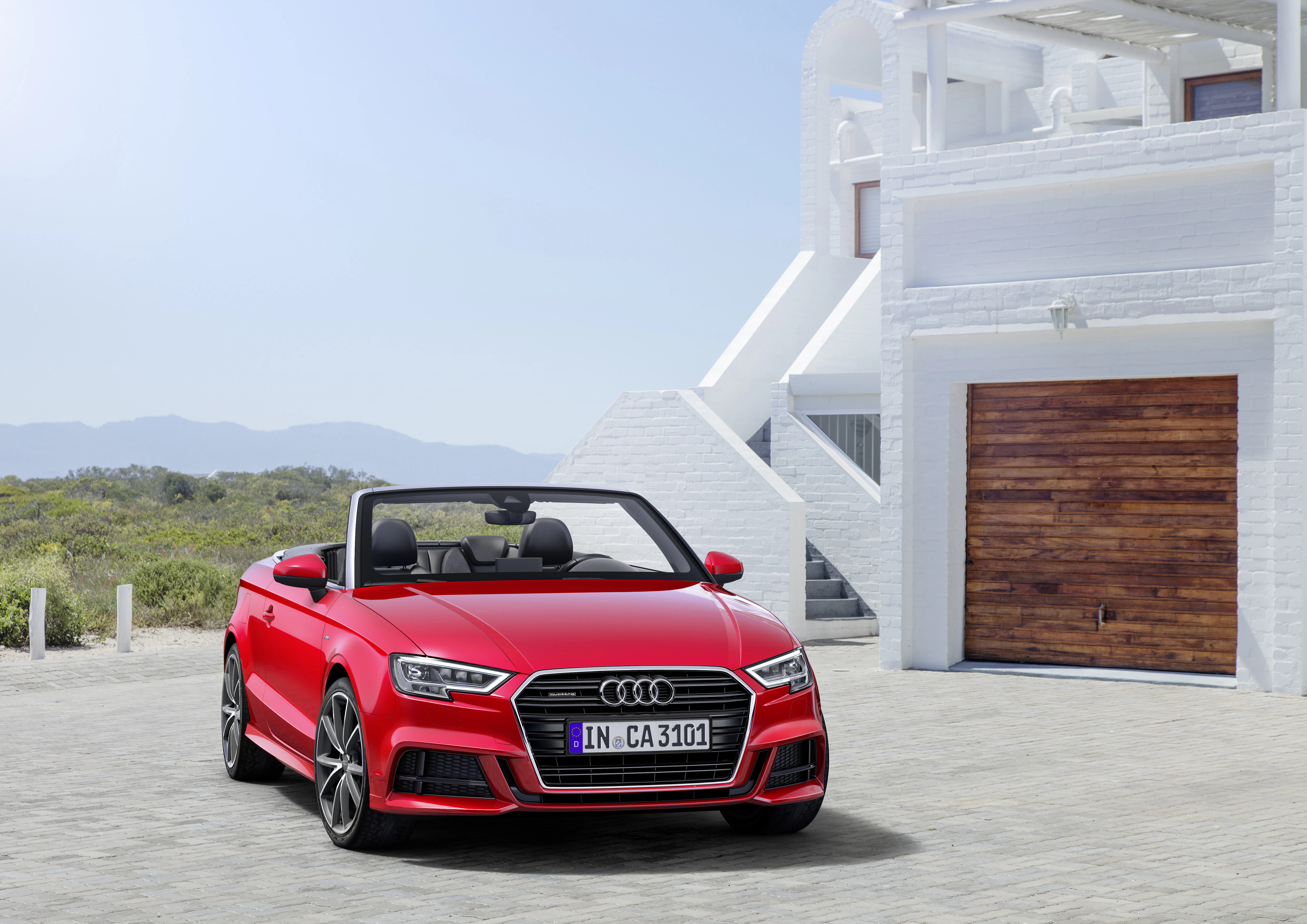 Rotes Audi Cabriolet vor modernem weißen Gebäude, sonniges Wetter.