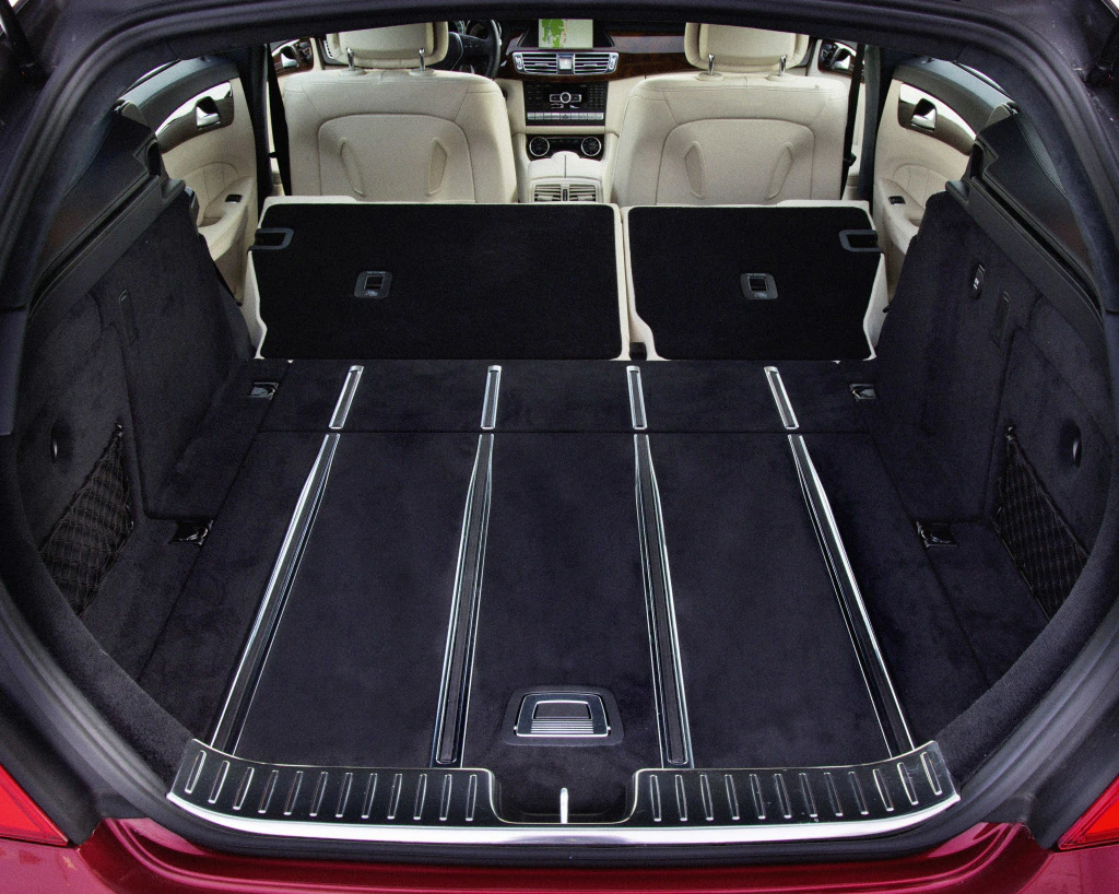 Kofferraum eines Autos mit umgeklappten Rücksitzen, um eine große, flache Ladefläche zu schaffen. Innenraum mit beigem Leder und modernem Armaturenbrett.