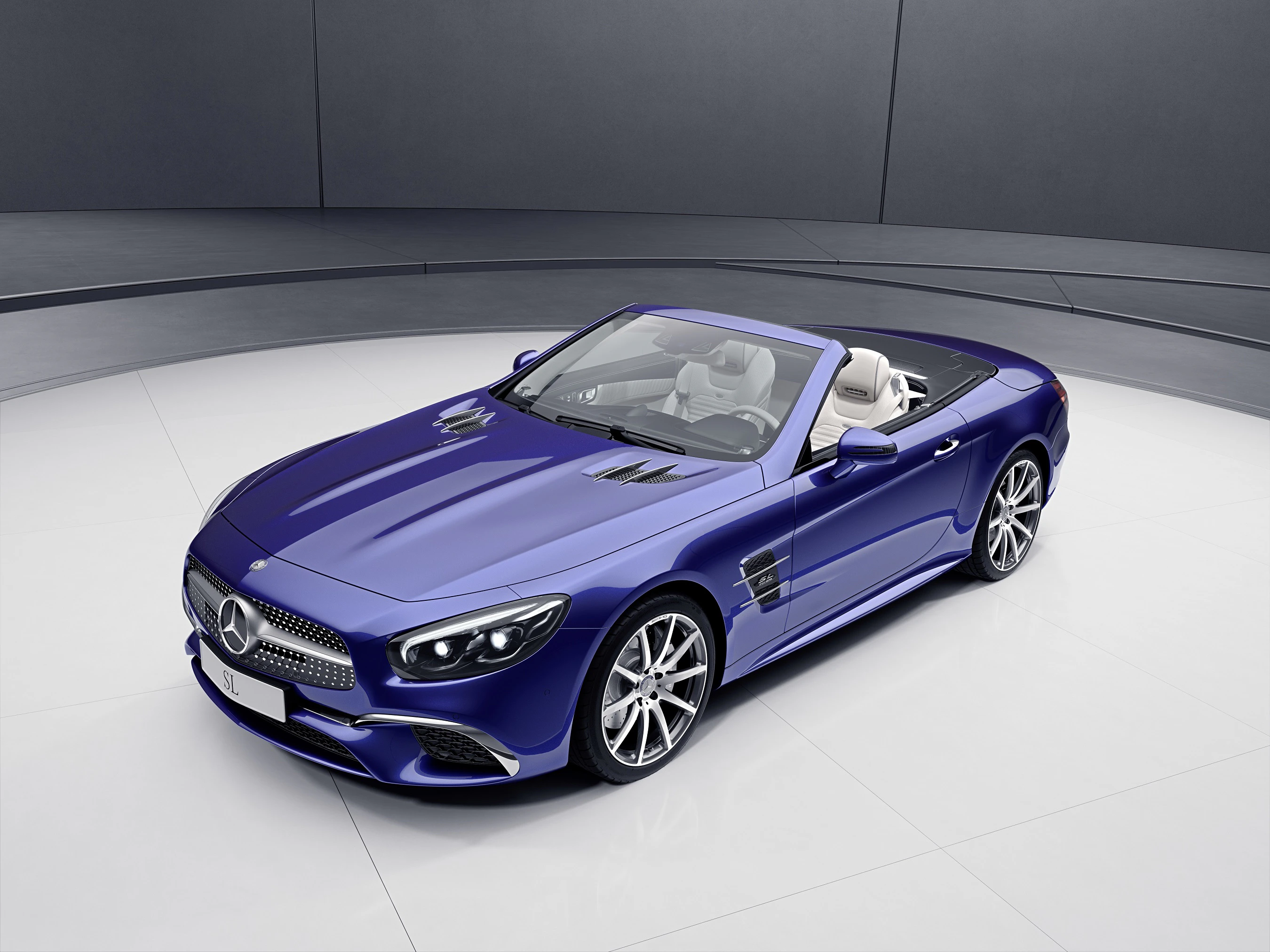 Blauer Mercedes-Benz Cabrio auf weißem Boden in einem modernen Raum. Fahrzeug mit offenem Verdeck und eleganten Linien.