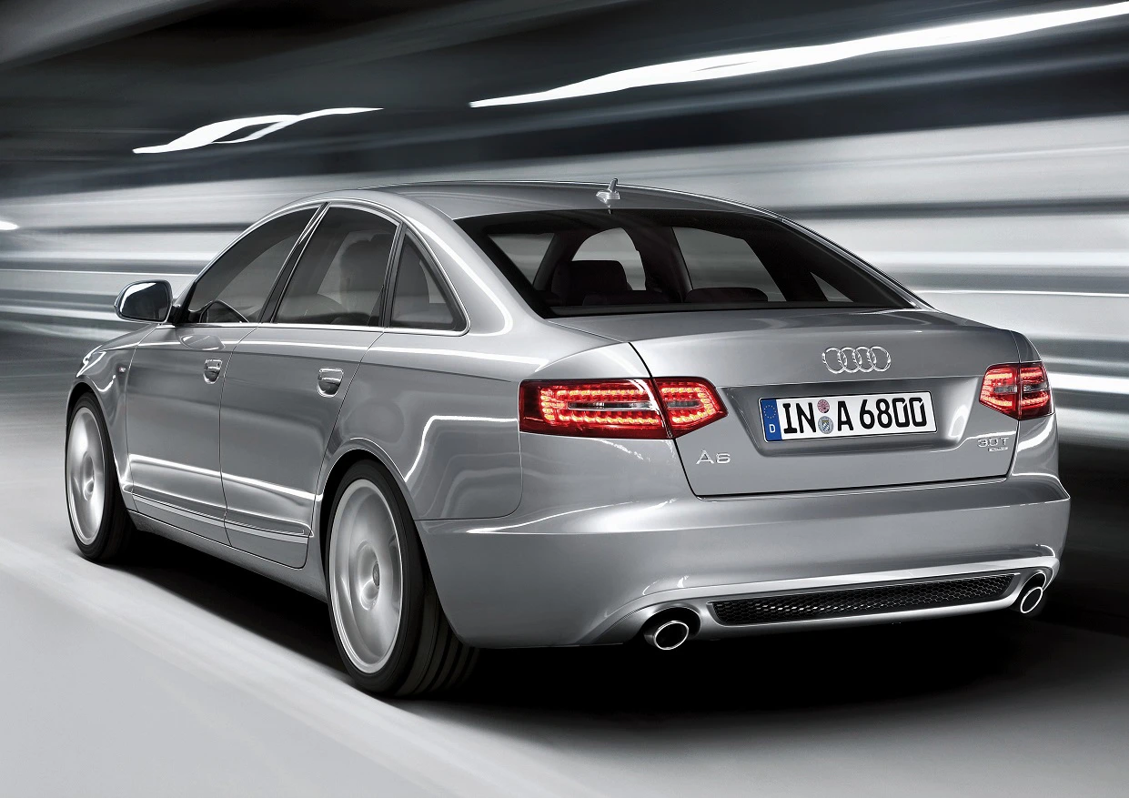 Silberner Audi A6 fährt dynamisch in einem Tunnel, Rückansicht. Bremslichter leuchten, verschwommener Hintergrund.