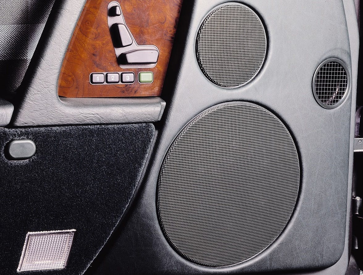 Kfz-Innentür mit Lautsprechern und Bedienelementen aus Holz und Metall.