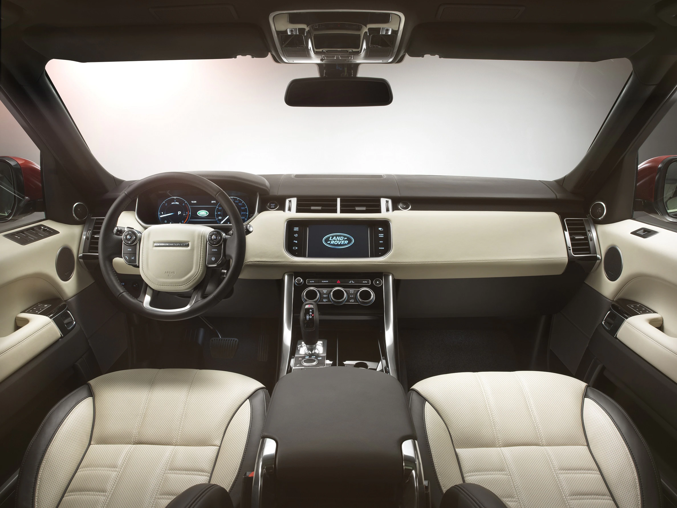 Innenraum eines modernen Autos mit beigen Ledersitzen, Lenkrad links, zentralem Bildschirm und eleganter Armaturenbrettgestaltung.