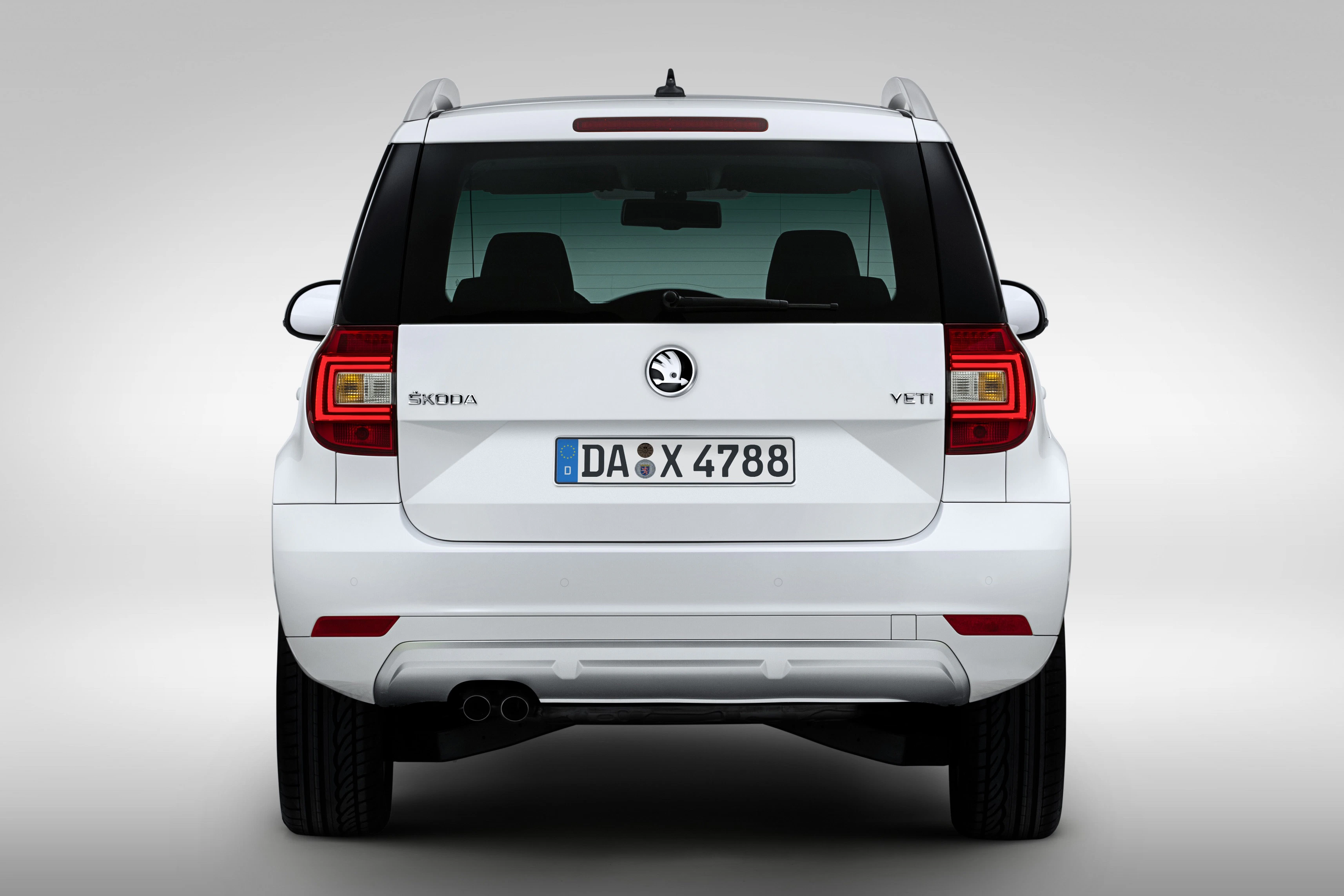 Rückansicht eines weißen Škoda Yeti mit deutschem Kennzeichen, klarer Hintergrund.